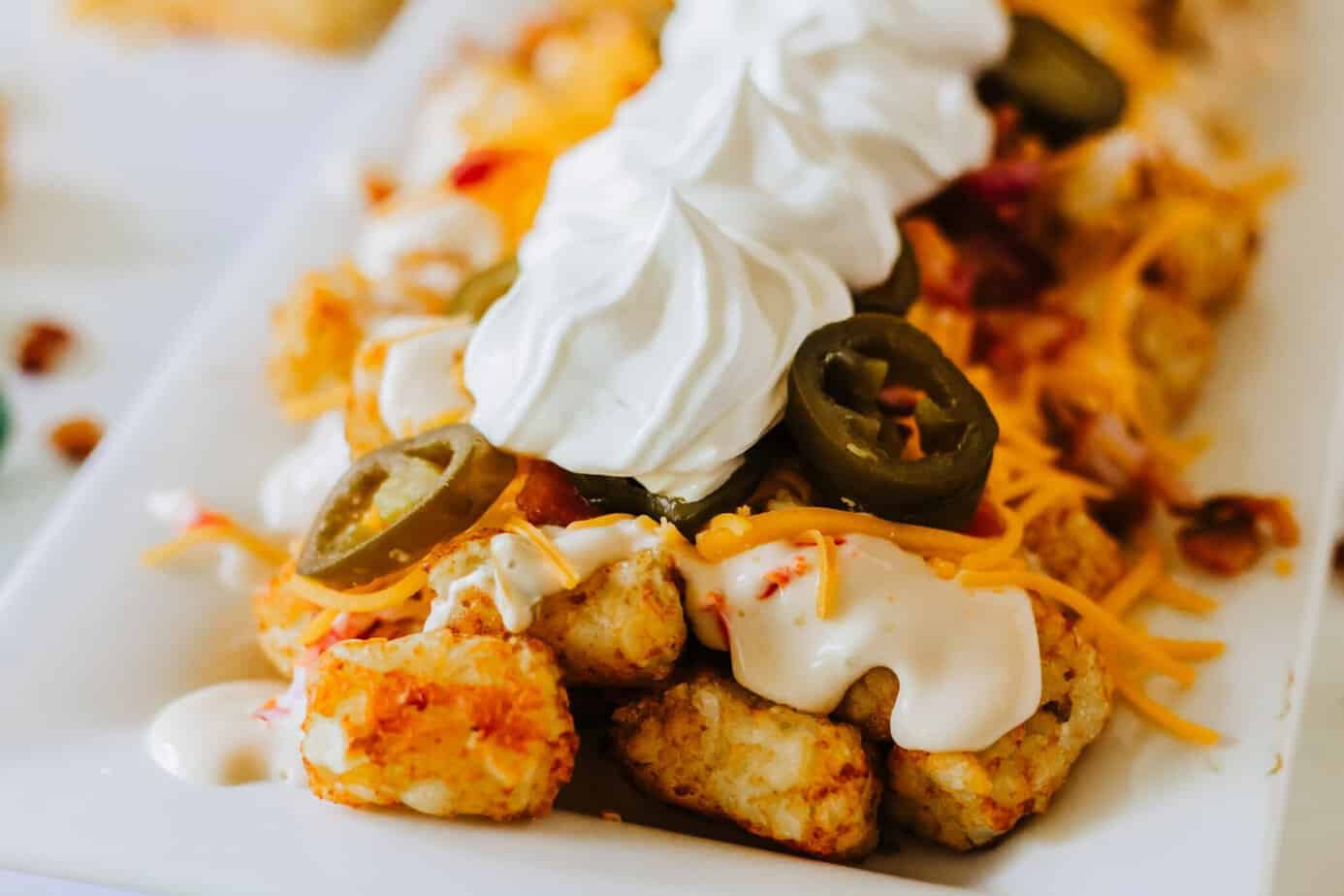 loaded tater tots with queso, shredded cheese, jalapenos, bacon and sour cream