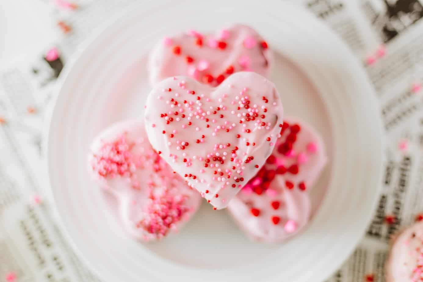 overhead view of a mini heart cake dipped in pink chocolate and Valentine sprinkles