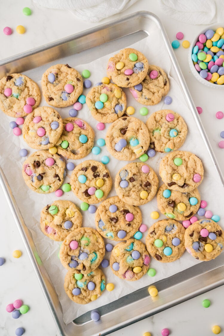baked easter cookies on a lined baking sheet with extra m&ms