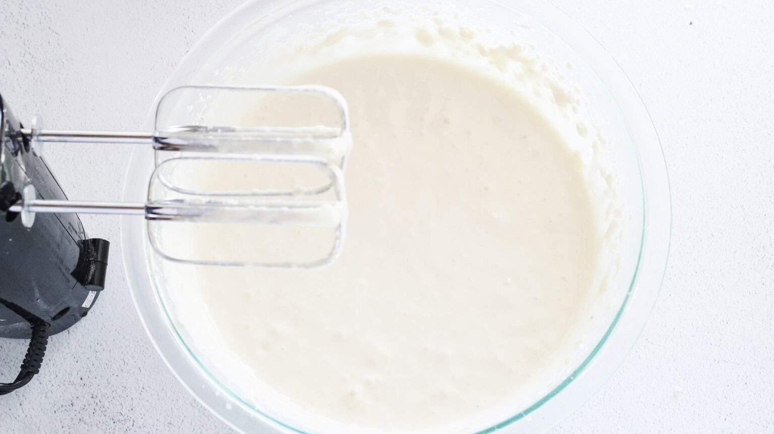 mixing cheesecake ingredients in a clear mixing bowl