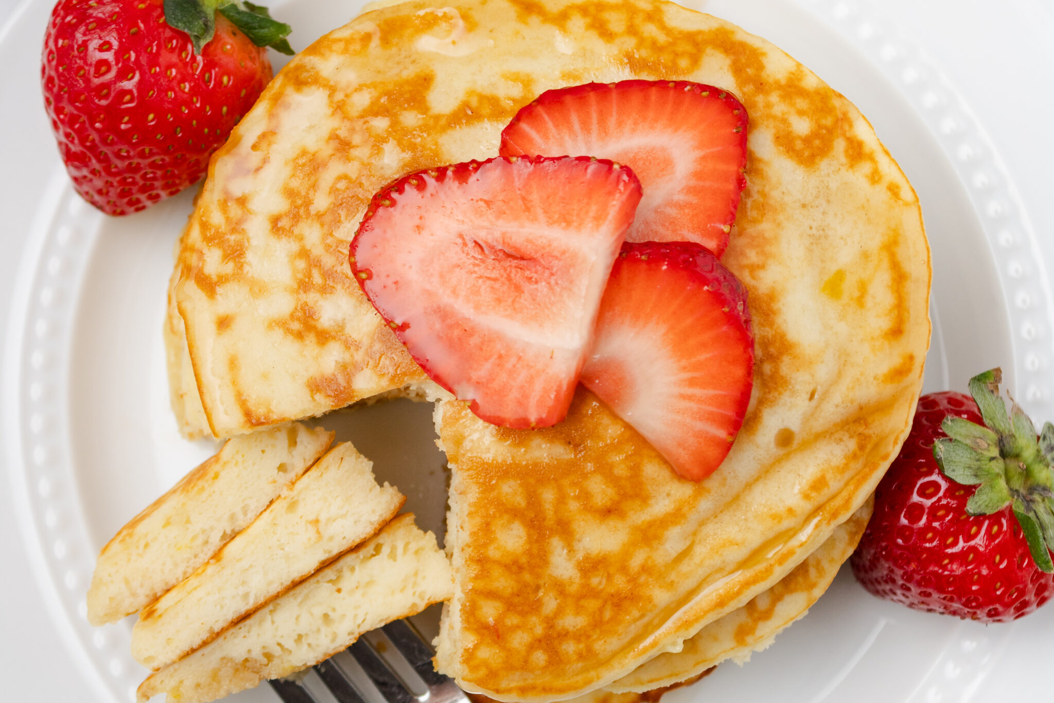 a stack of lemon ricotta pancakes with a wedge cut out