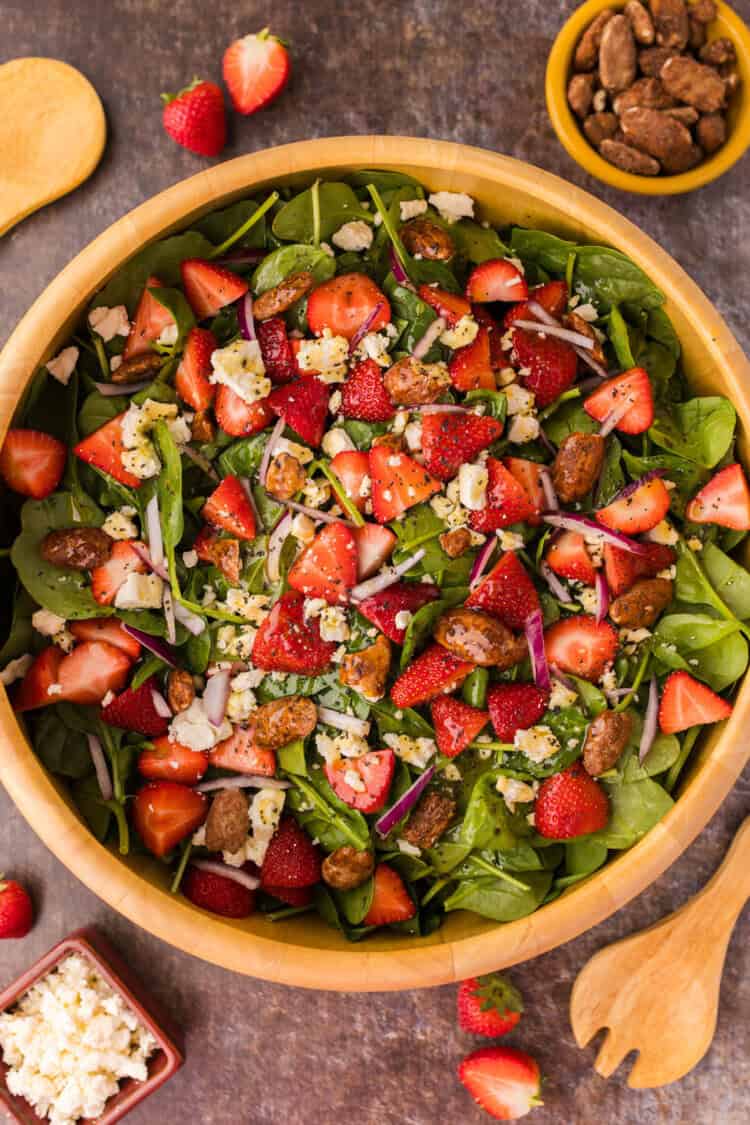Strawberry Feta Spinach Salad in a round wooden bowl on a gray surface