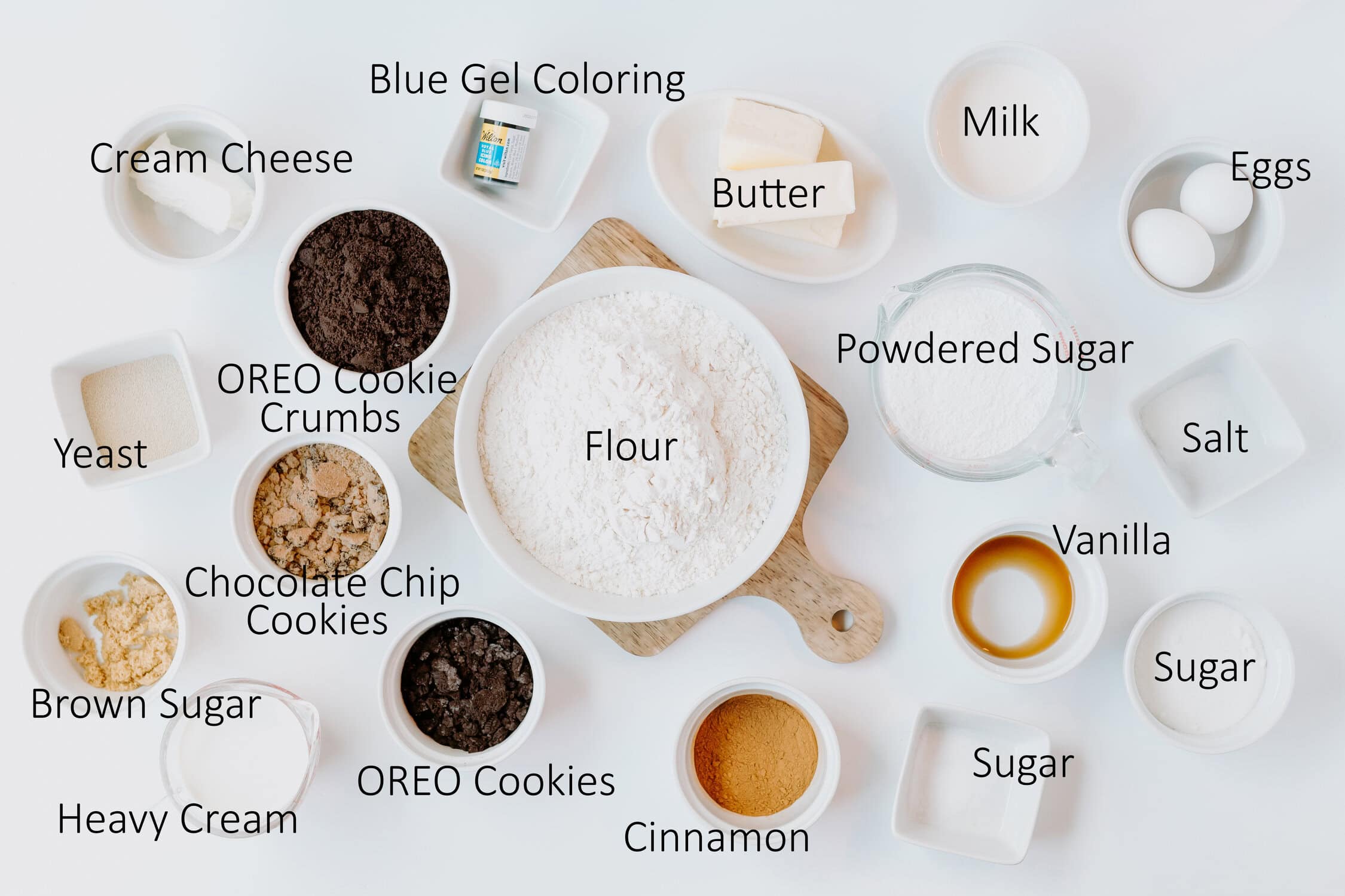 ingredients for cookie monster cinmamon rolls in individual bowls on a white surface