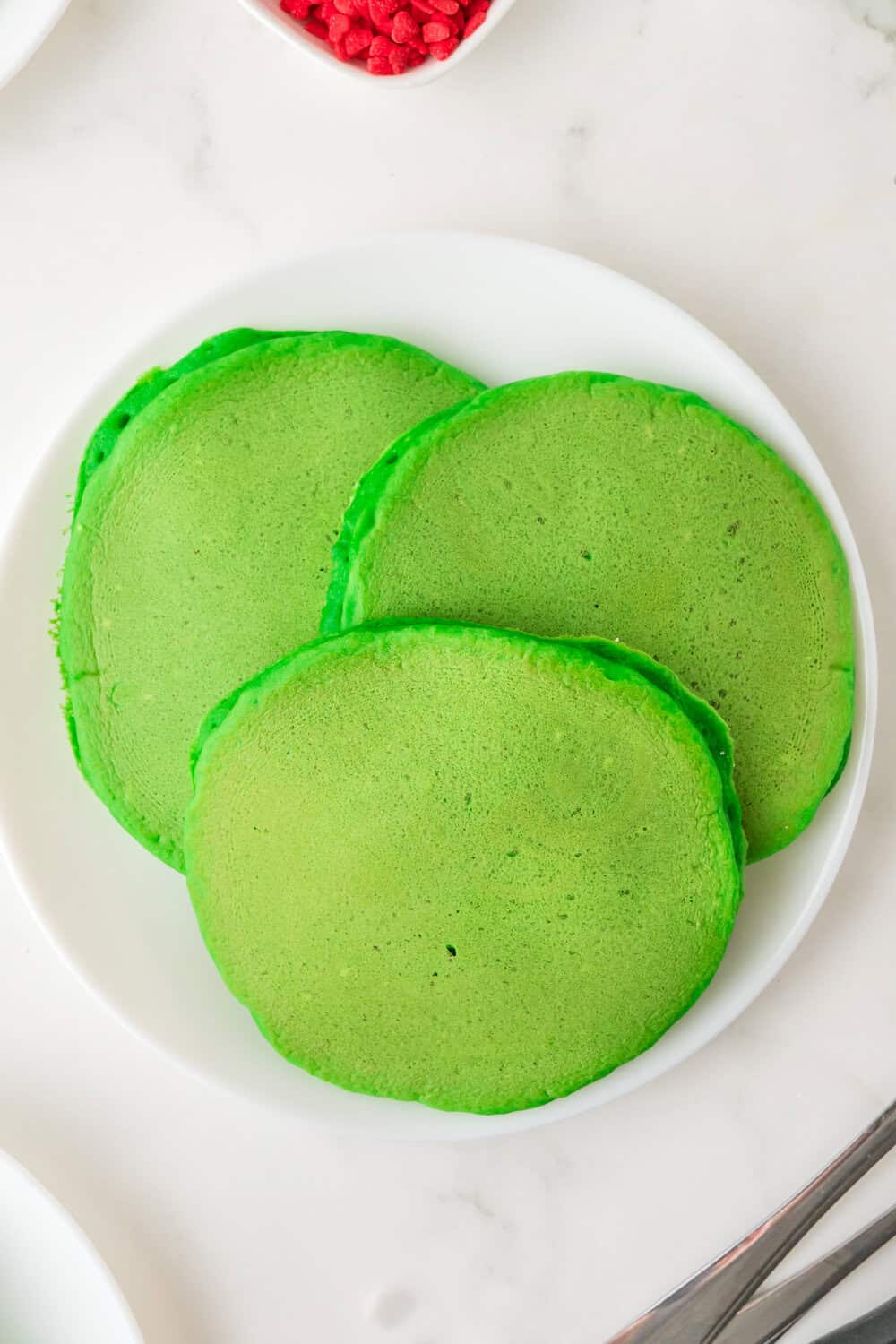 cooked green grinch pancakes on a white plate