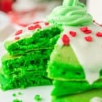 a stack of grinch pancakes with a wedge cut out