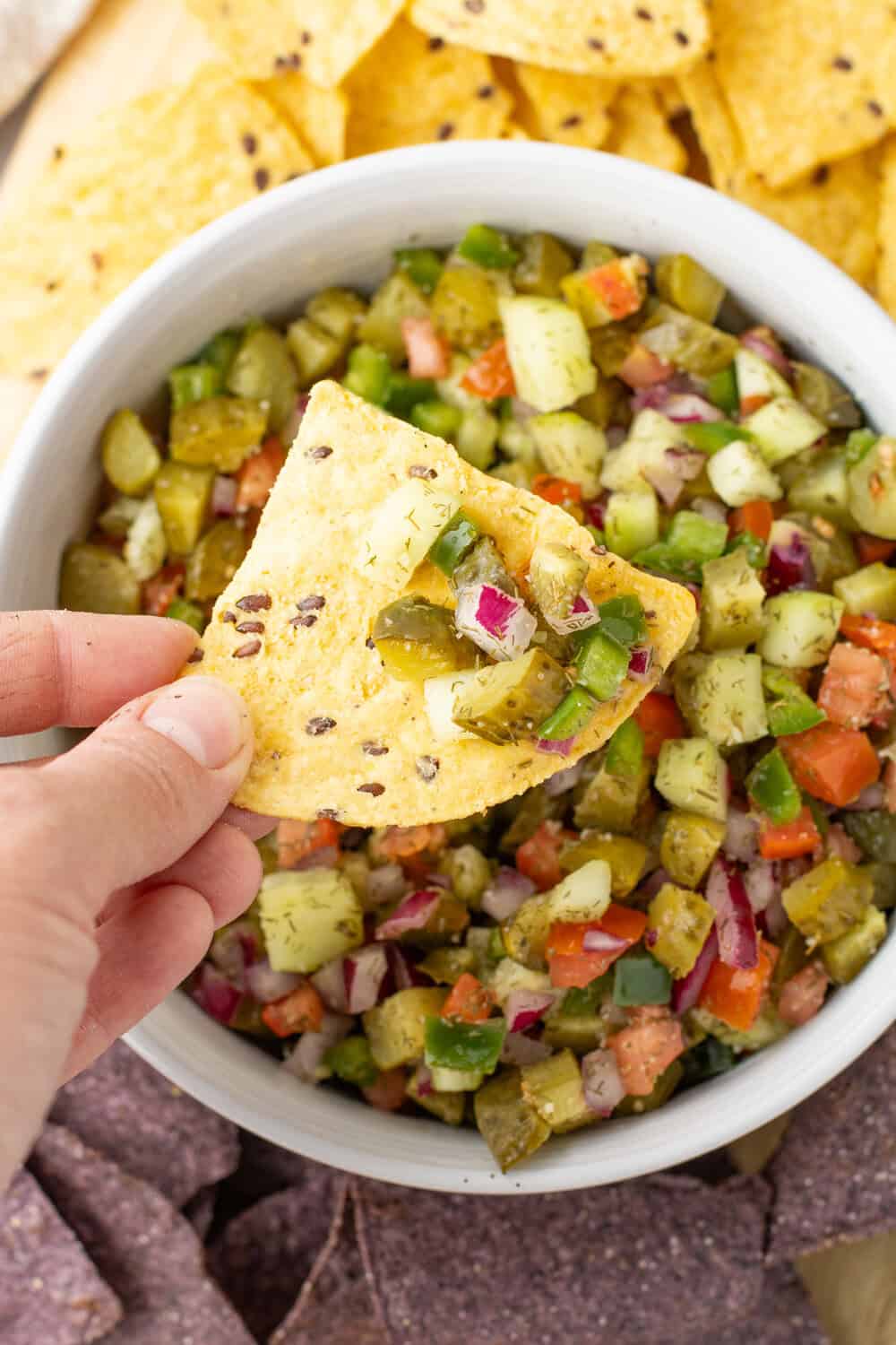 a bowl of pickle de gallo with a scoop of it on a chip