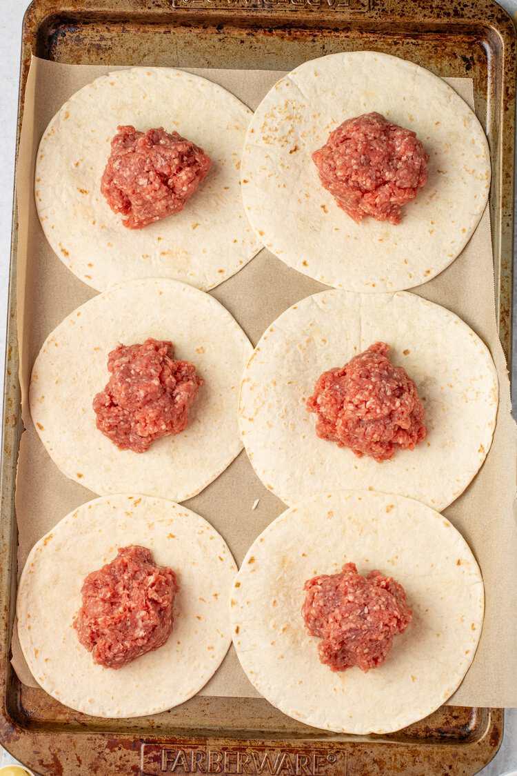 balls of ground beef on tortillas on a pan