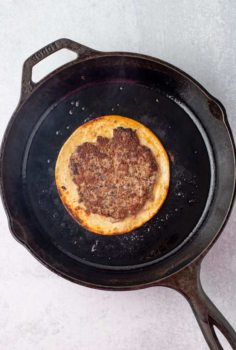 smash burger on a tortilla in a cast iron skillet