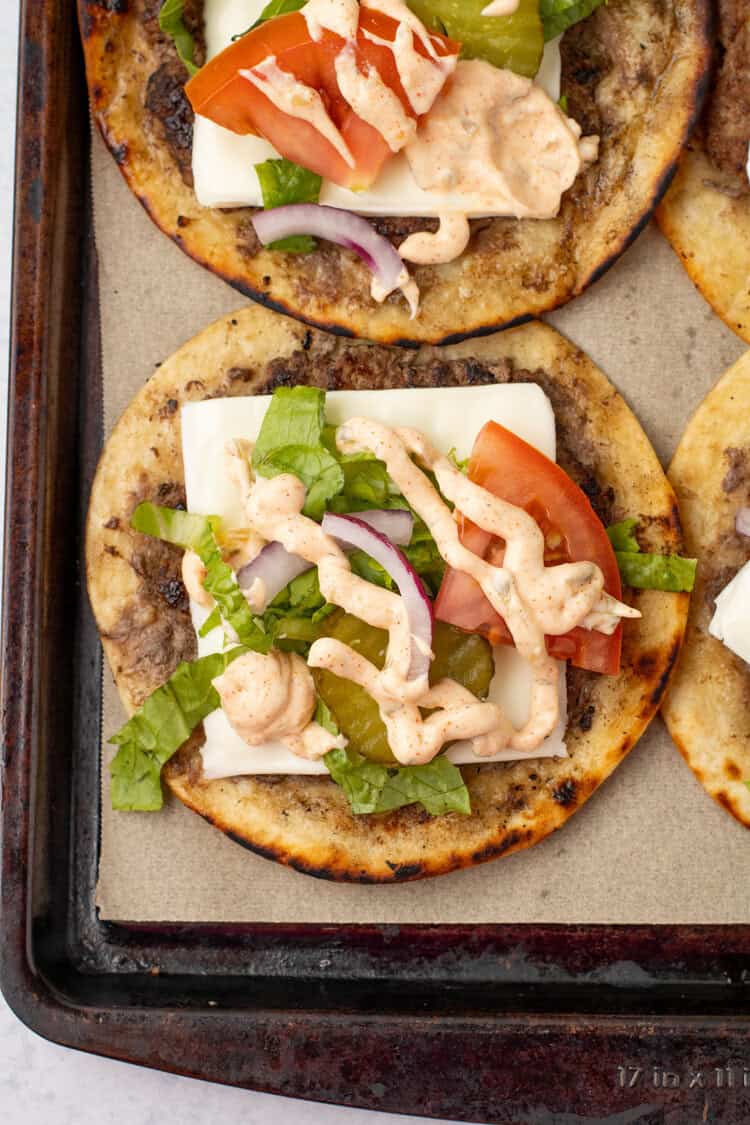 smash burger tacos dressed on a cookie sheetl ined with parchment