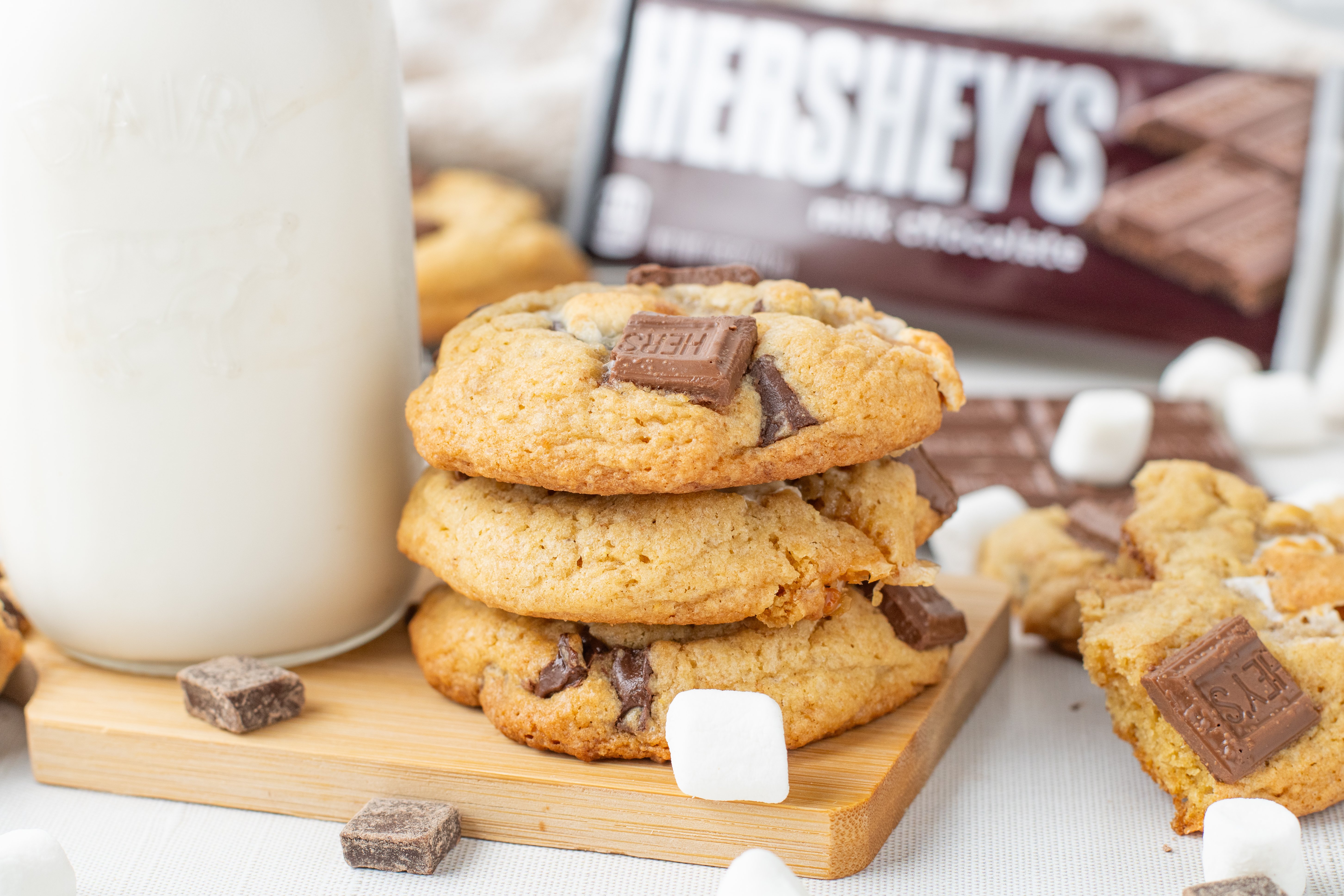 S'mores Cookies stacked on a cutting board next to a glass of milk