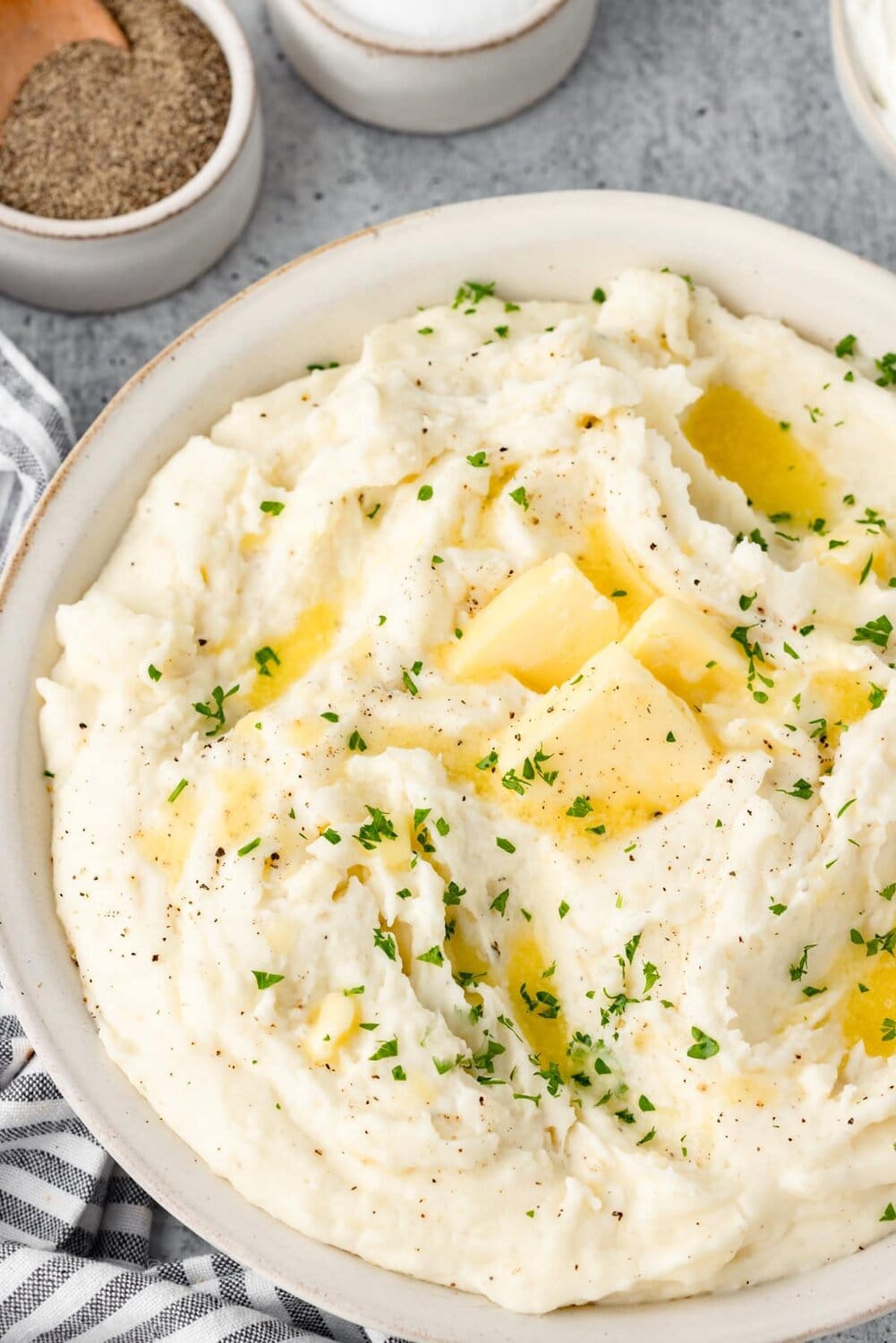 Sour cream mashed potatoes with pats of butter melting on top.