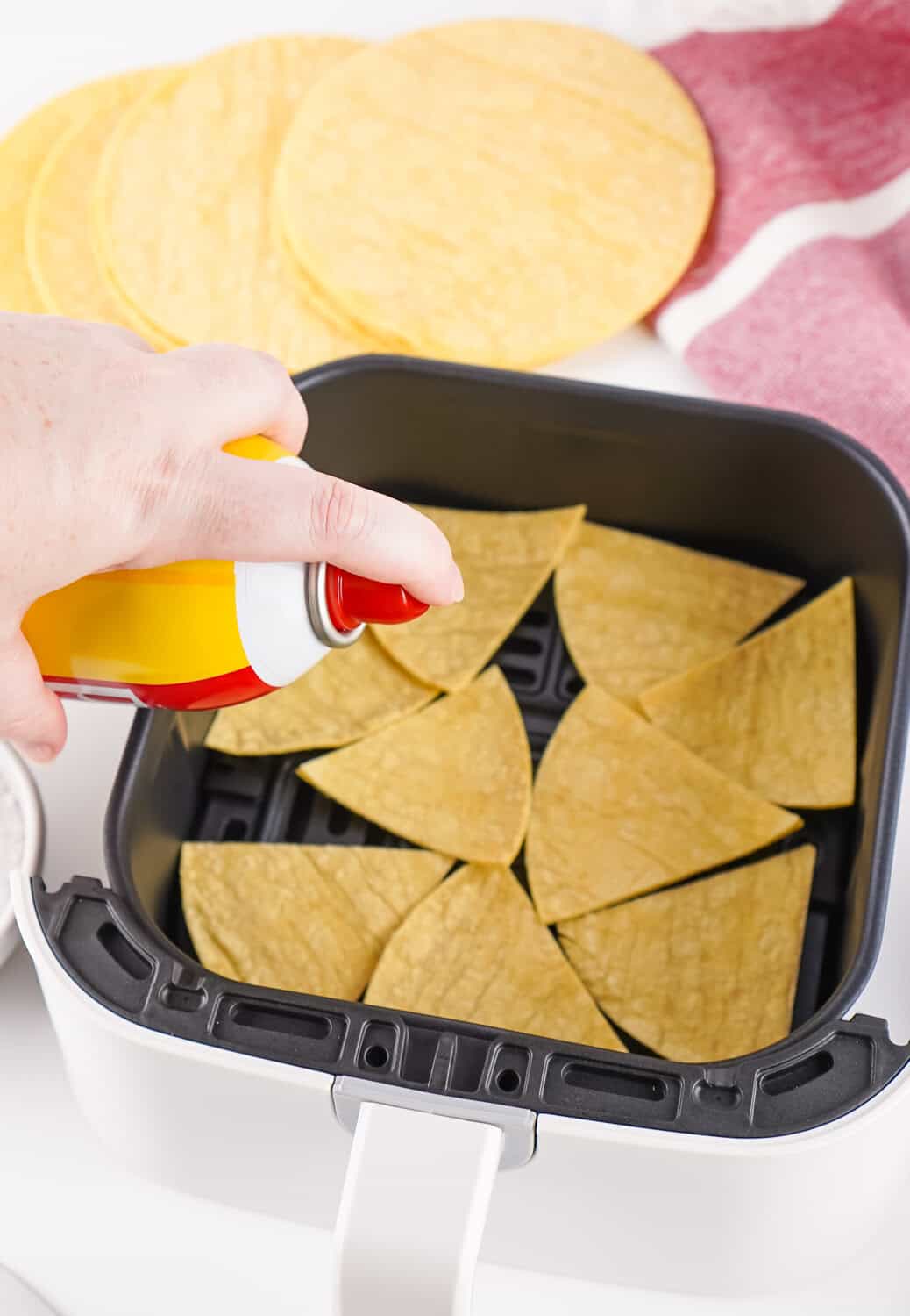 spraing tortilla triangles in air fryer with cooking spray