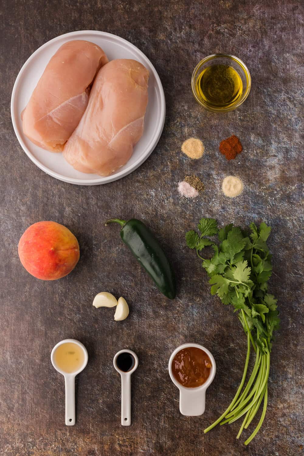 Ingredients for Jalapeno Chicken with Peaches on a dark surface