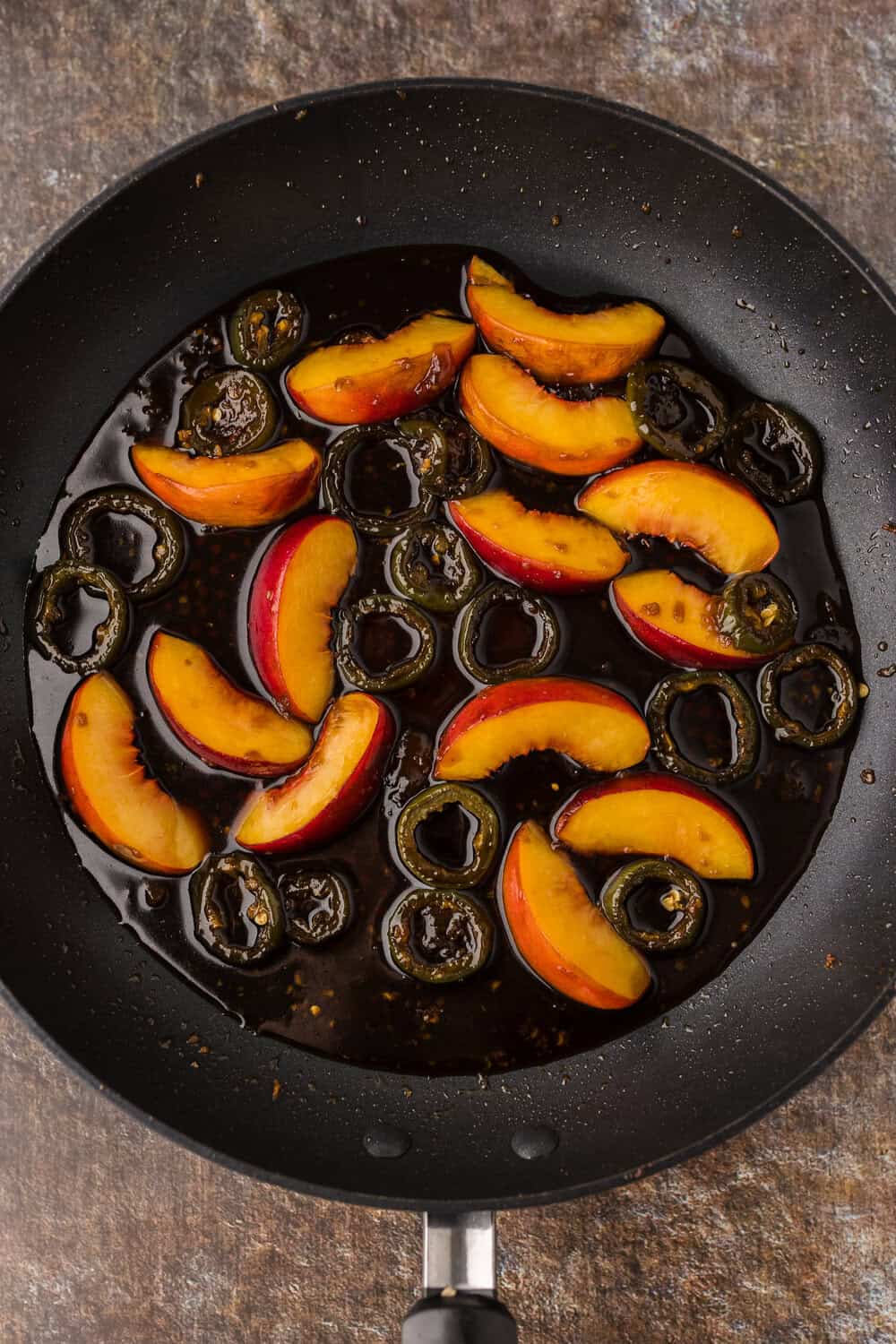 peaches and jalapenos in a glaze in a skillet