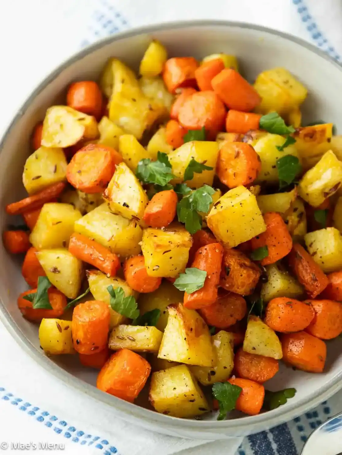 Roasted potatoes and carrots in a serving bowl.