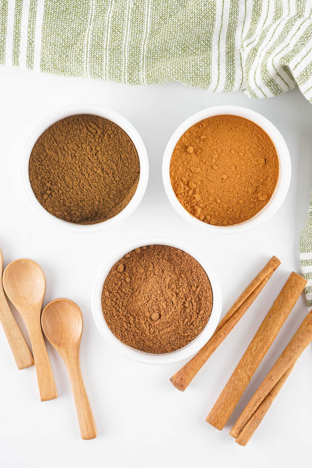 homemade allspice ingredients - bowls of ground cinnamon, ground cloves, and ground nutmeg