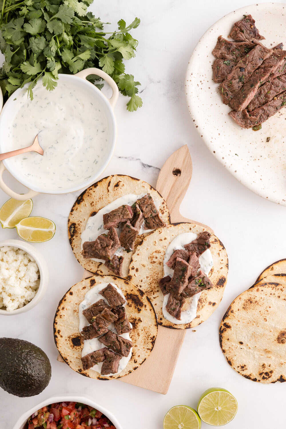 carne asada meat on a warm corn tortilla with Cilantro Garlic Lime Crema