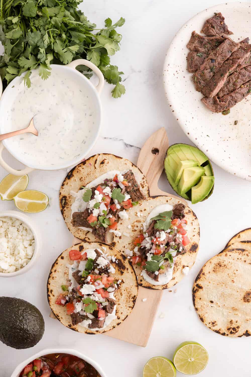 carne asada tacos topped with pico de gallo, onion and avacado