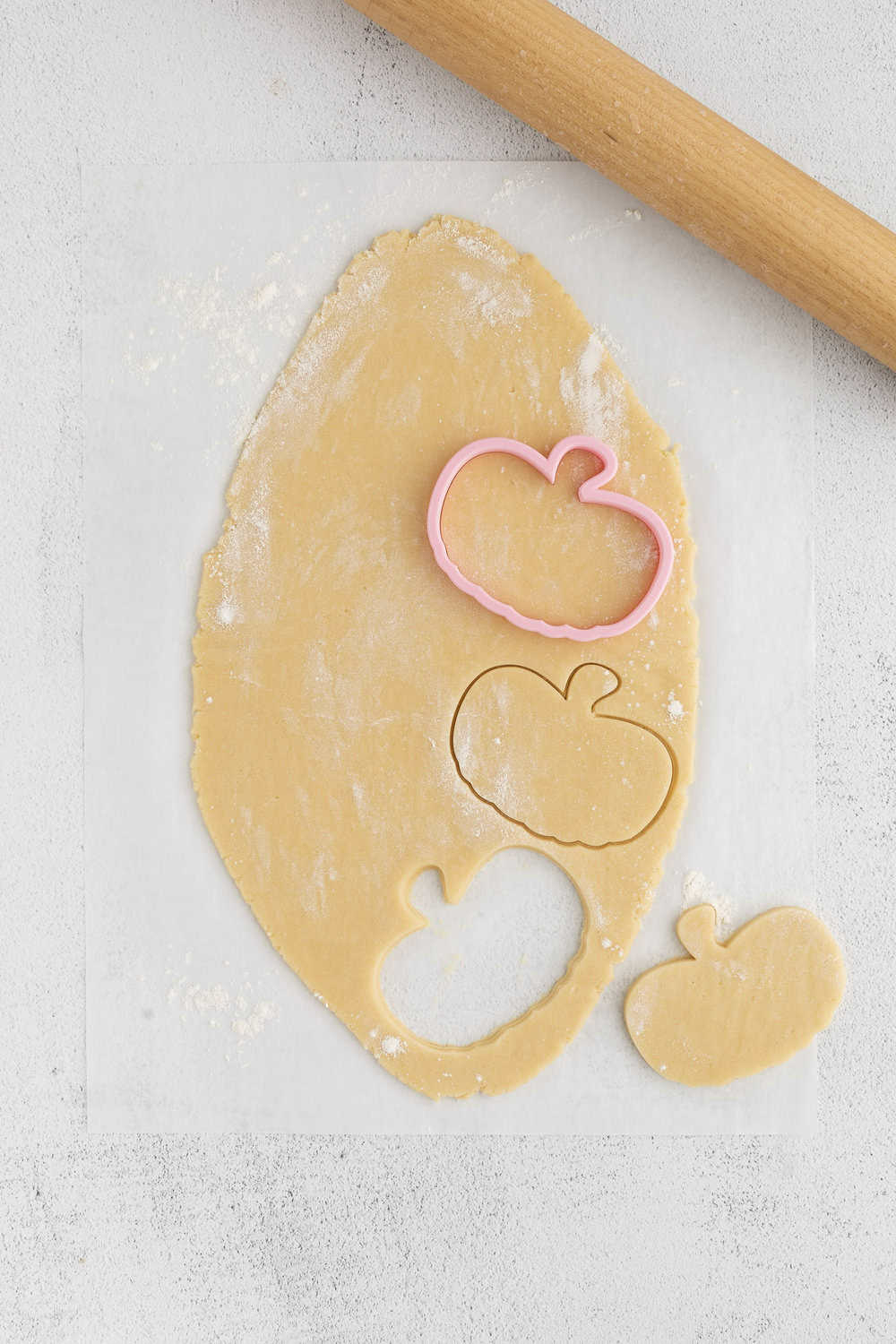 dough rolled out on a surface and pumpkin-shapes cut out