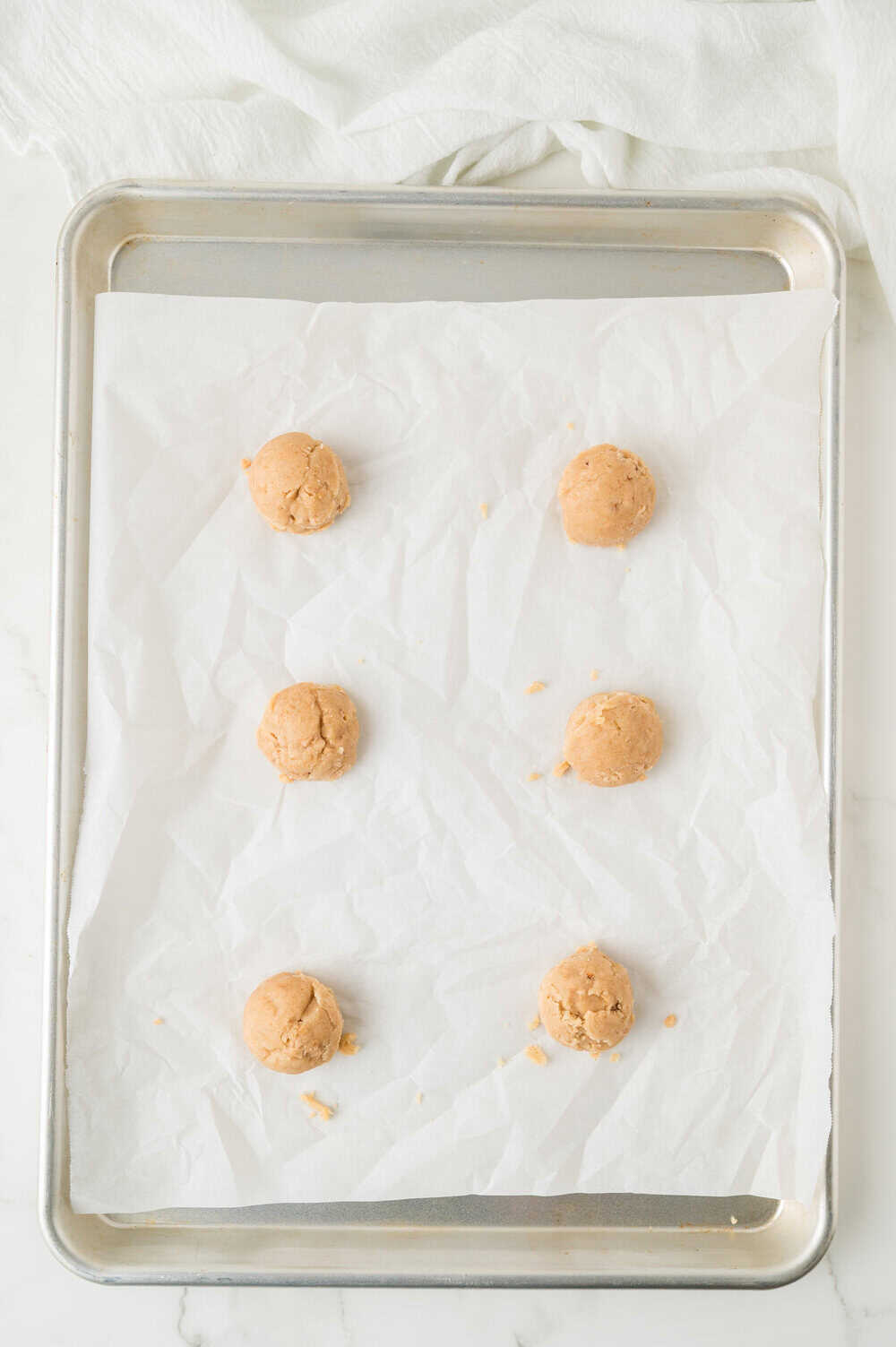 balls of butter crisp cookie dough on a parchment lined cookie sheet