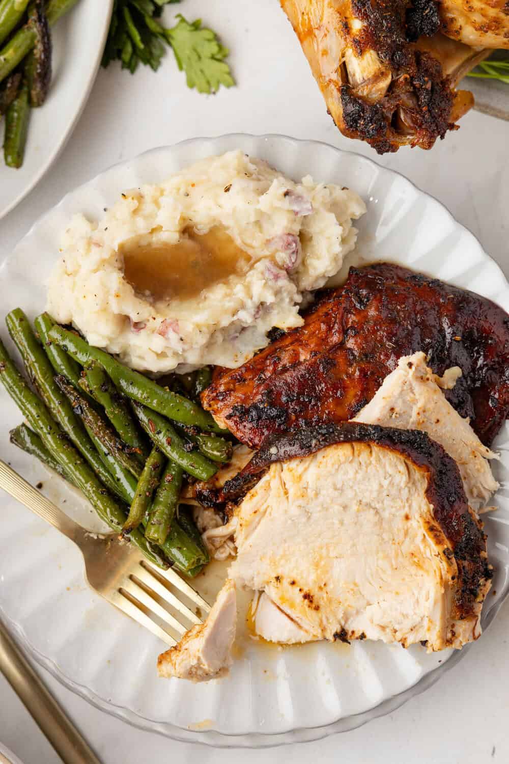 cajun turkey on a plate with mashed potatoes and gravy and green beans