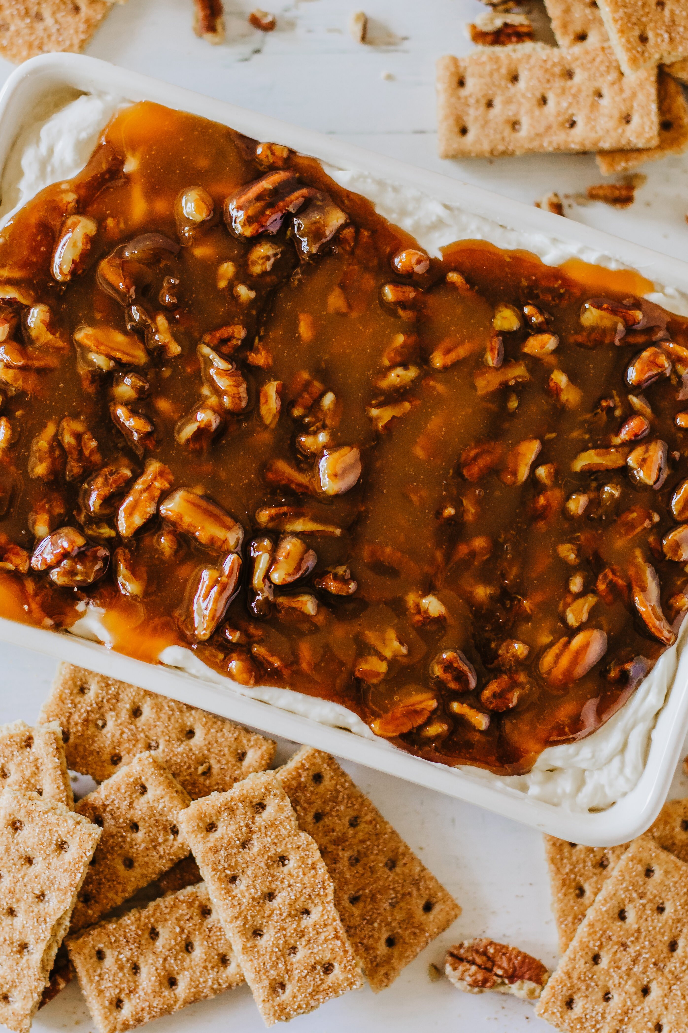 pecan pie dip in a white dish surrounded by cinnamon graham crackers