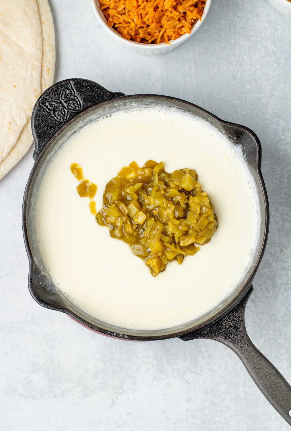 diced green chiles in the skillet with the melty cheese