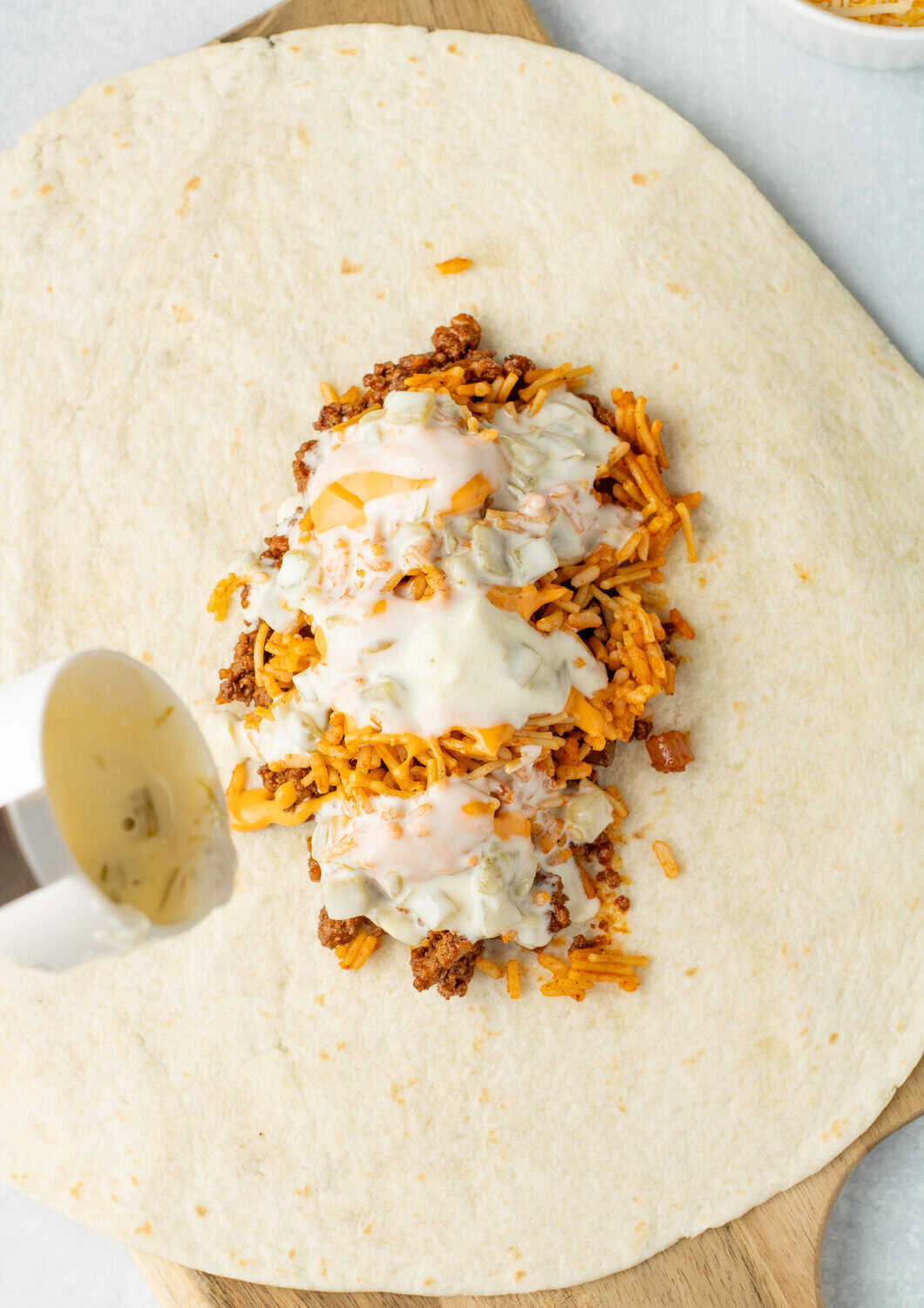 queso puored over other 5 layer burrito ingredients