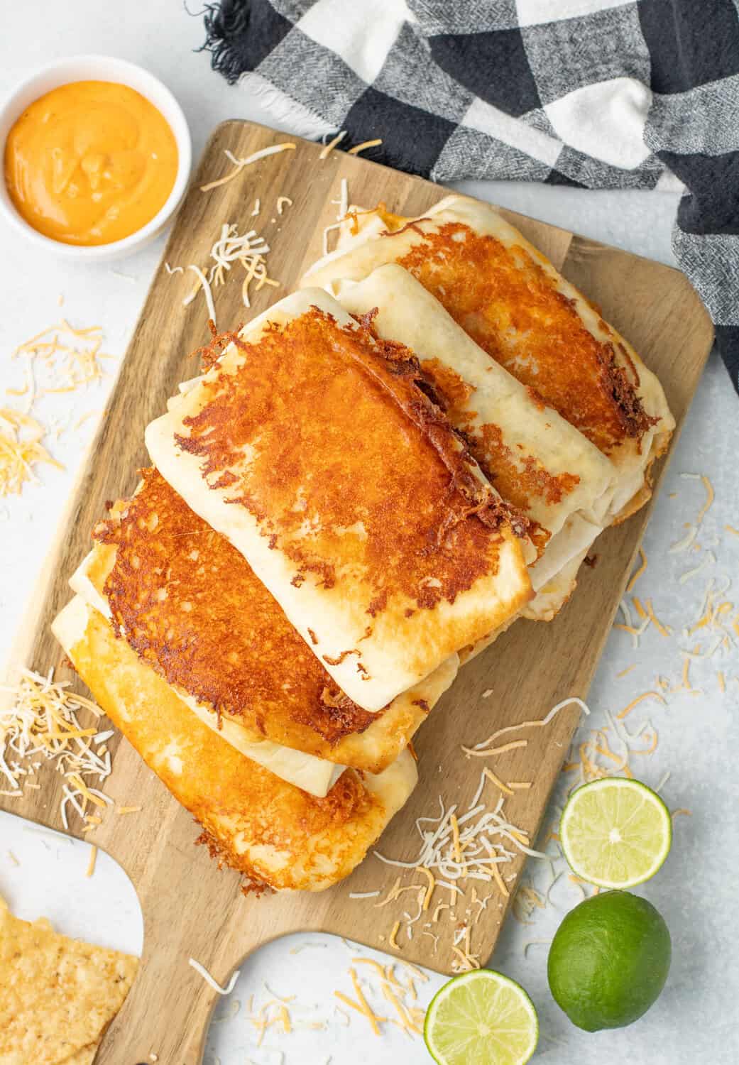 grilled cheese burritos stacked on a cutting board