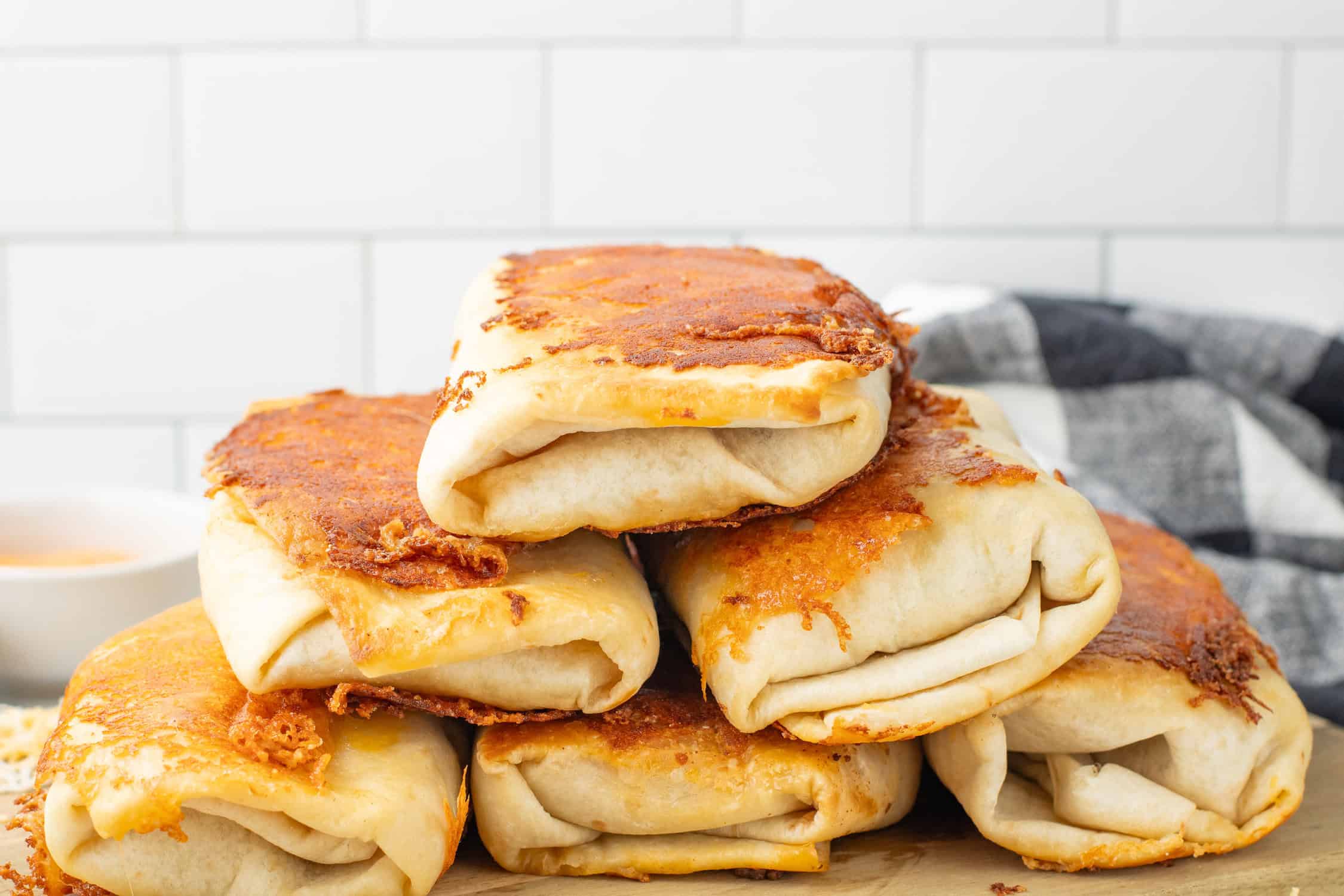 stack of grilled cheese burritos on a cutting board