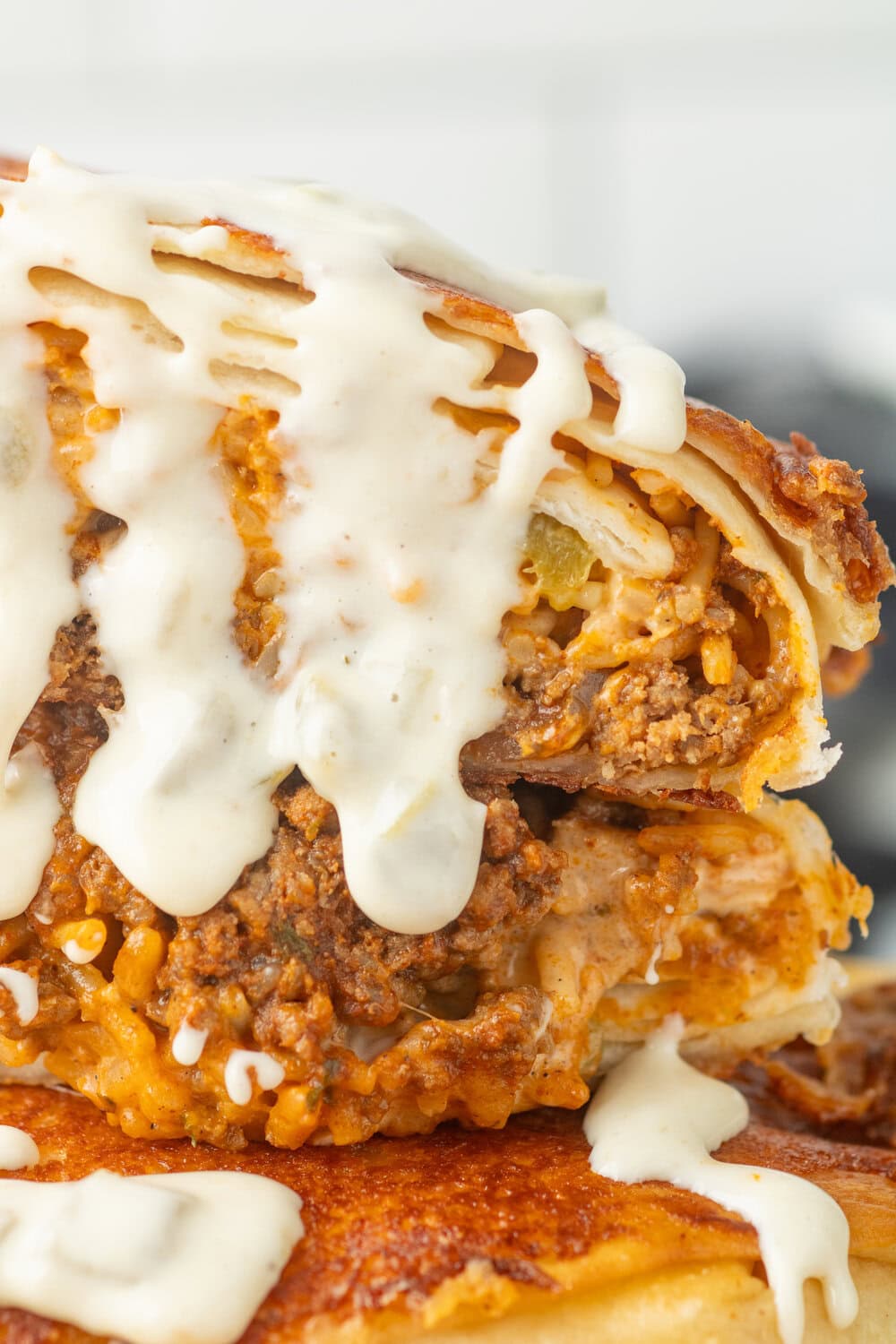 grilled cheese burrito cut in half and stacked with queso dripping off the top