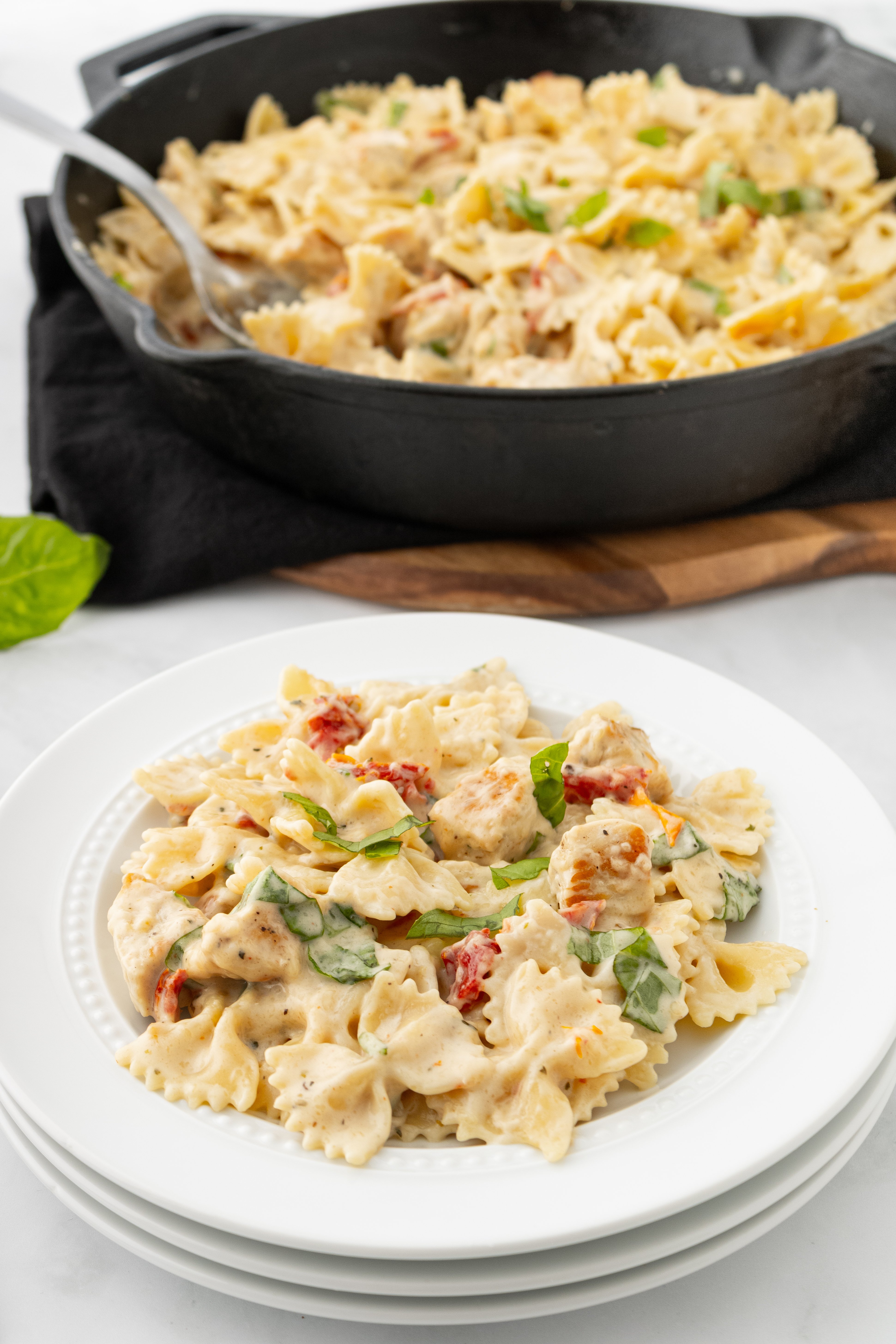 a plate of marry me chicken pasta in front of the skillet