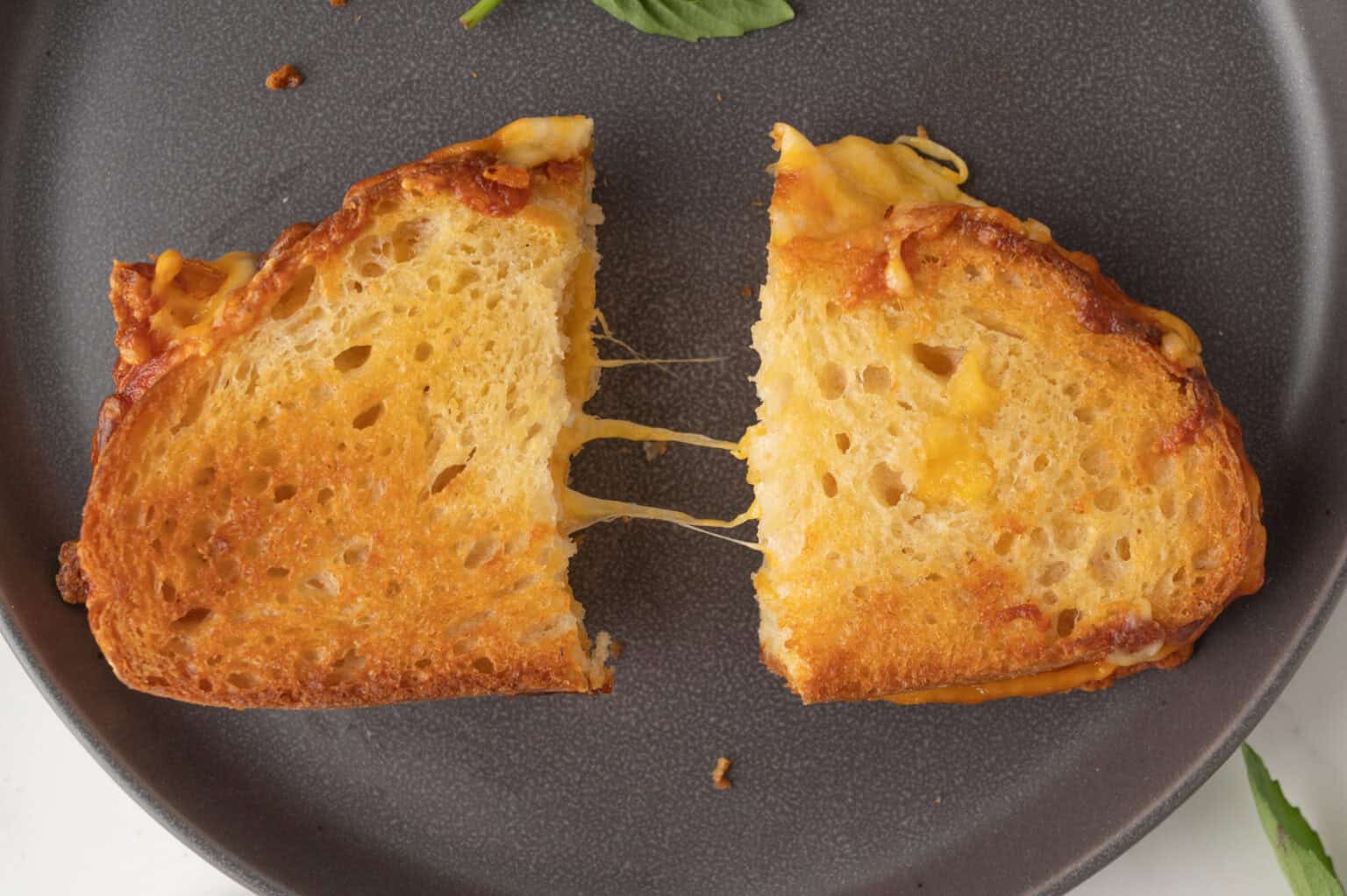 air fryer grilled cheese sandwich cut in half with cheese pull between the halves