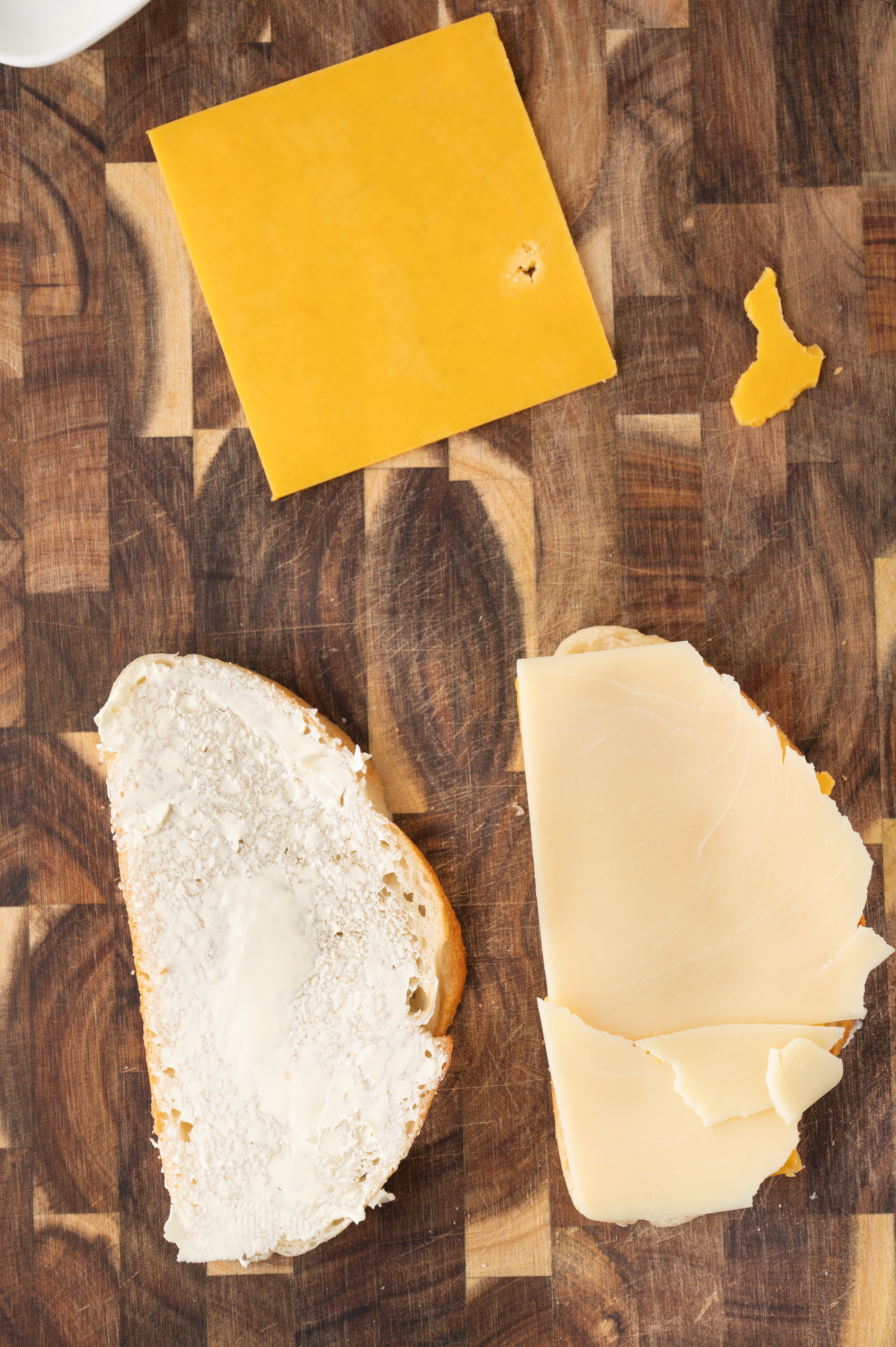 a slice of buttered sourdough bread and a slice with cheddar and mozzarella cheese on it
