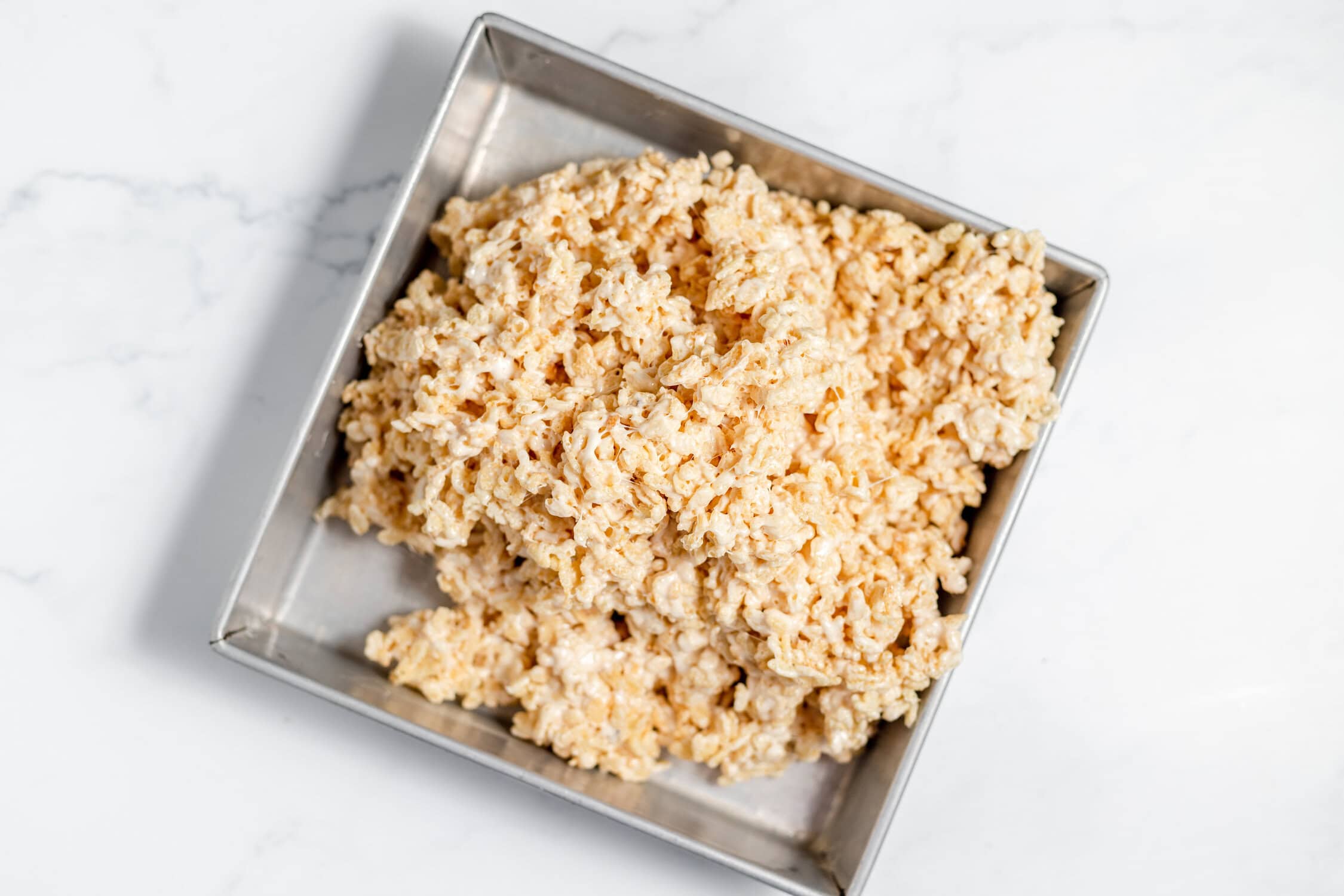 browned butter rice krispies in square pan before being pressed down flat