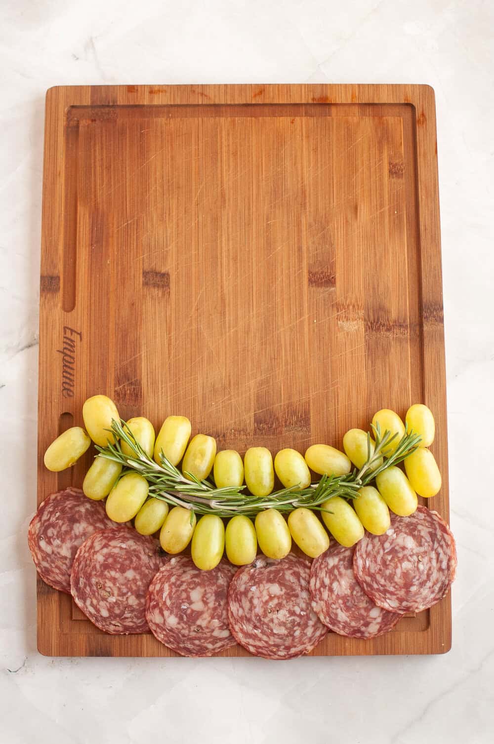 grapes and rosemary added to the cutting board for the Grinch smile