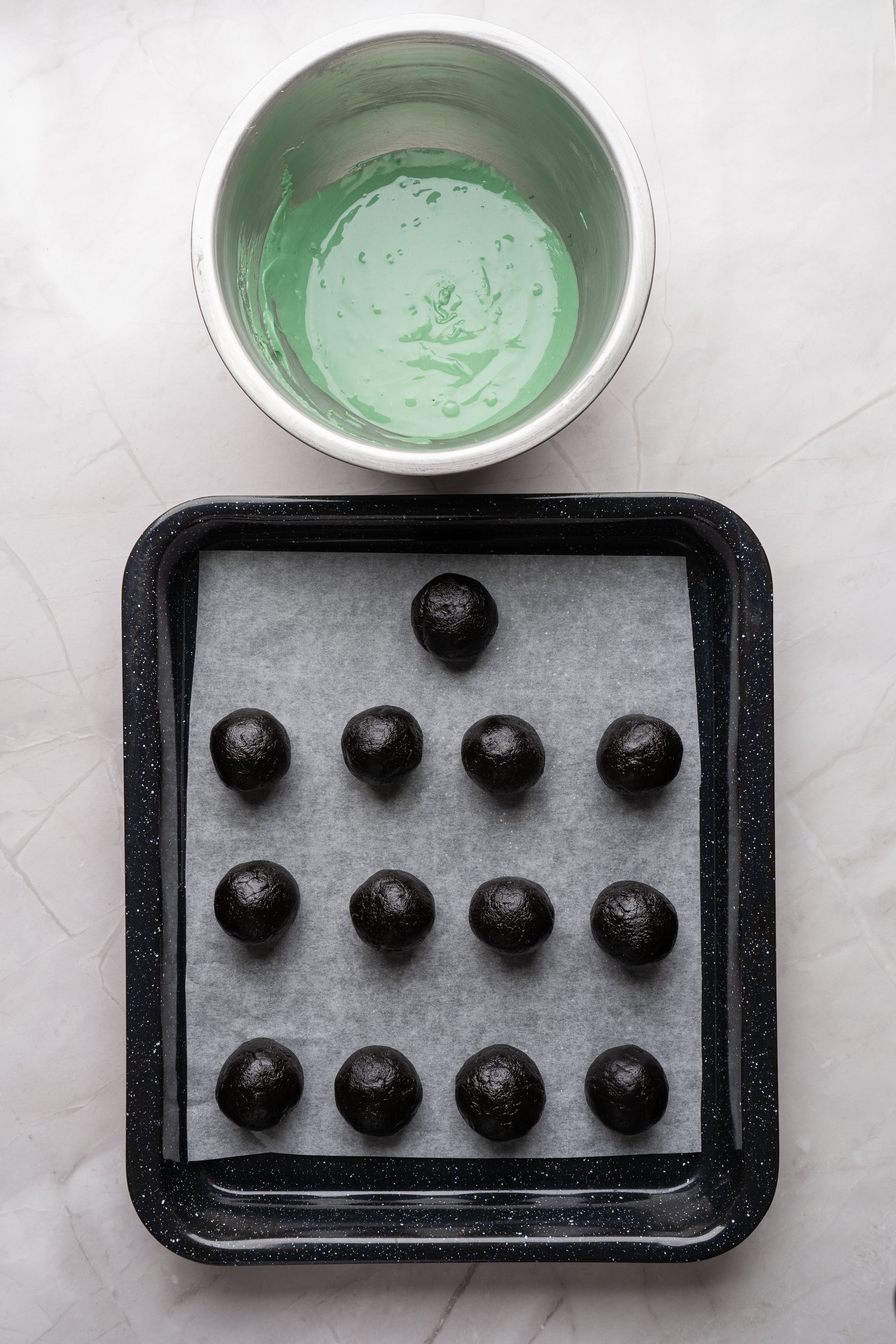 green candy melts in bowl next to tray of oreo balls
