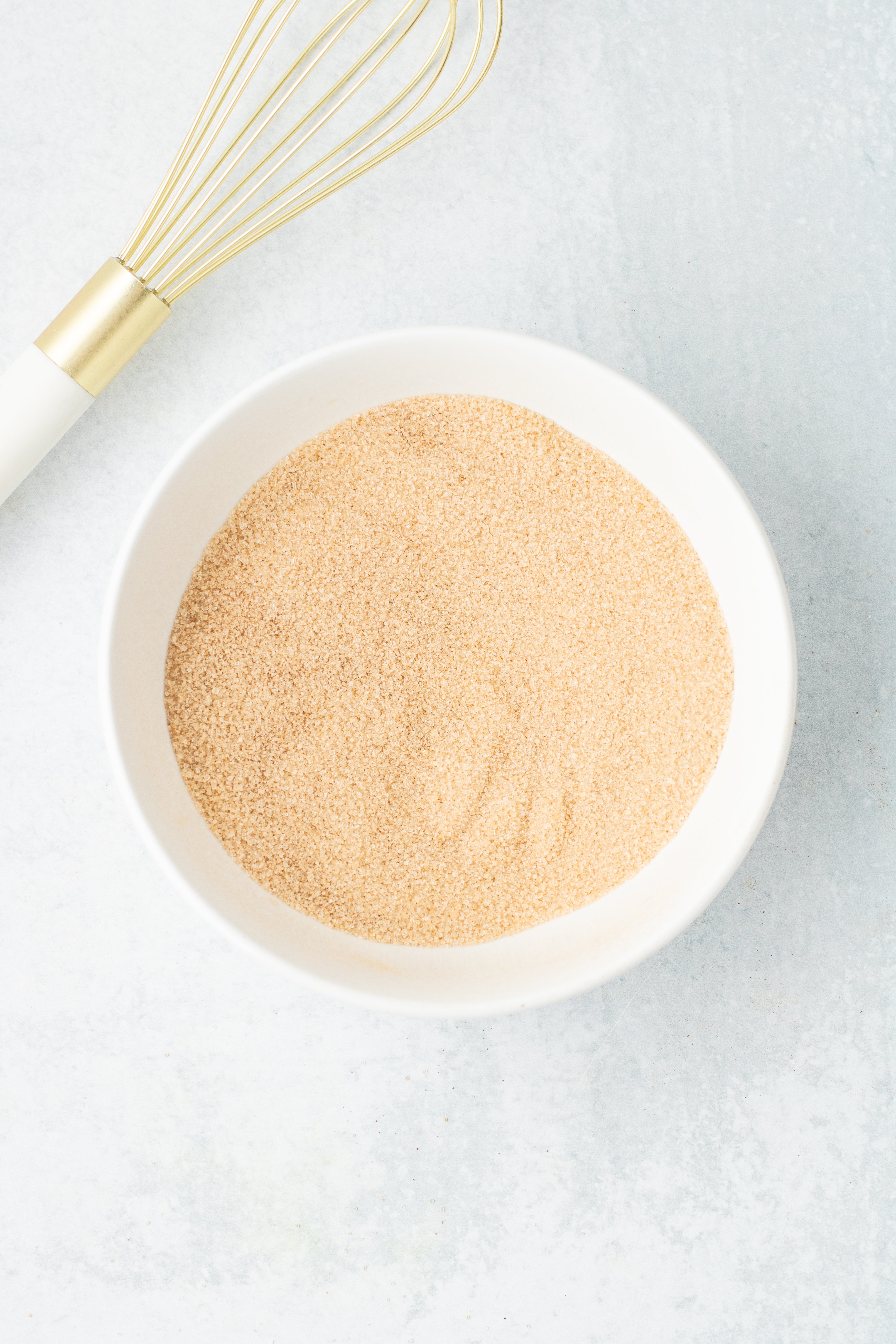 cinnamon sugar in a white bowl with a whisk next to it