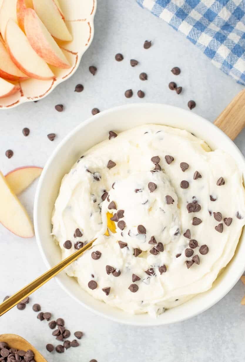chocolate chip dip in a white bowl with sliced apples off to the side on a plate