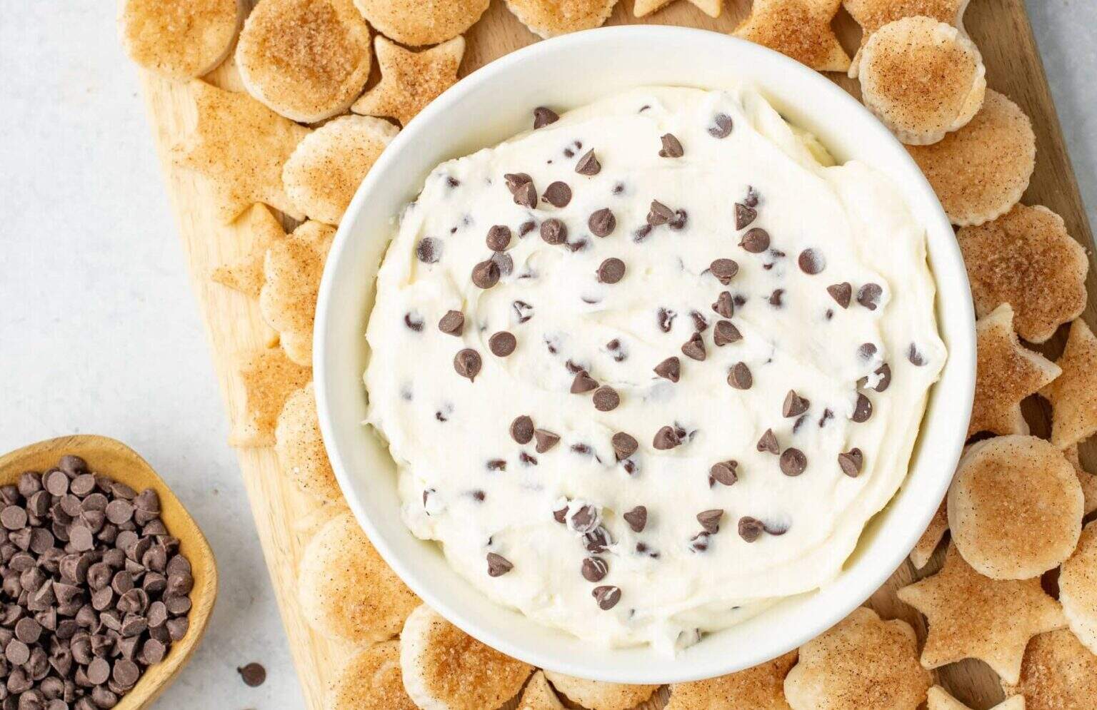 cheesecake dip surrounded by pie crust cookies on a cutting board