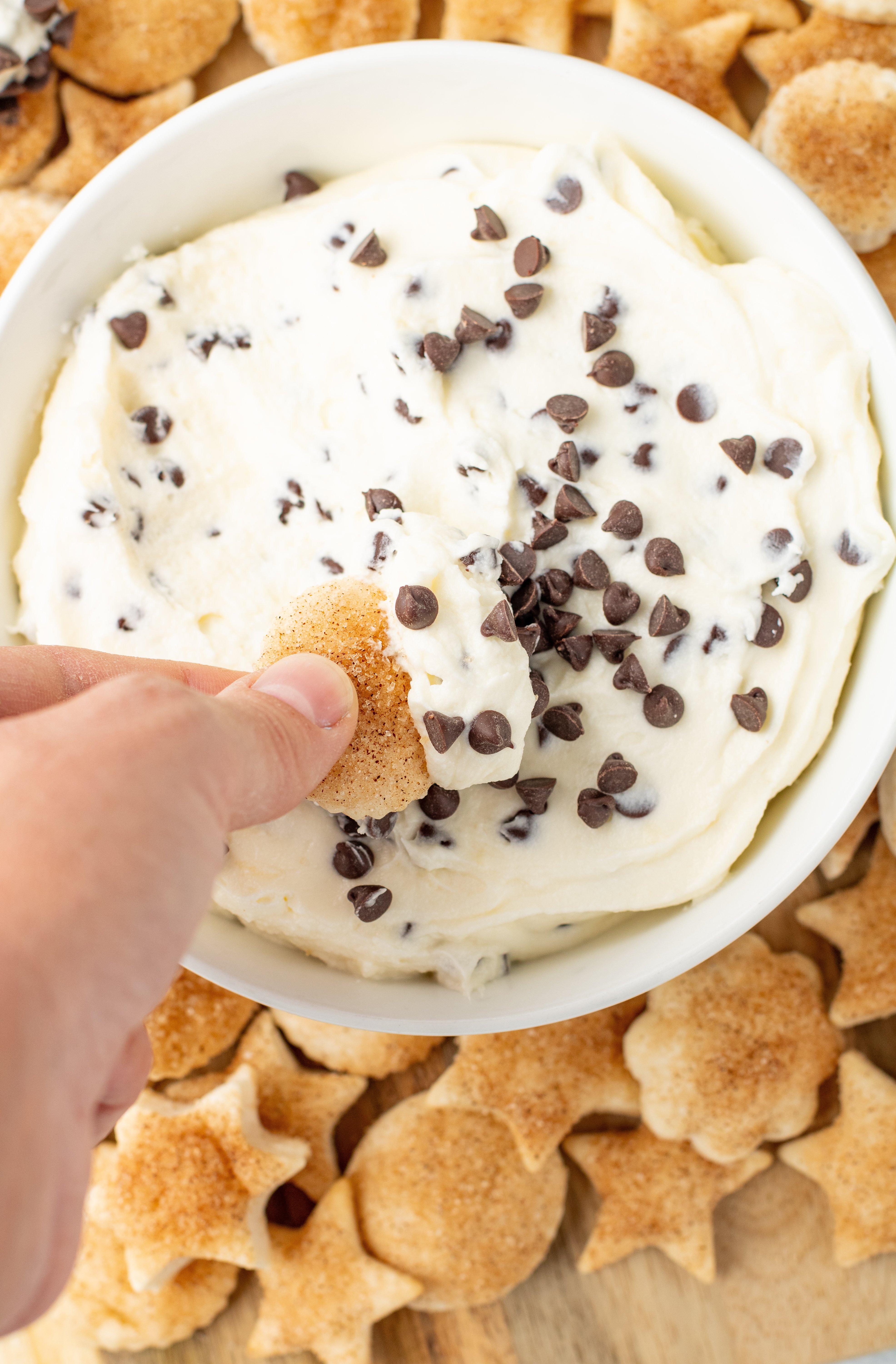 cheesecake dip with chocolate chips being dipped with pie crust cookie