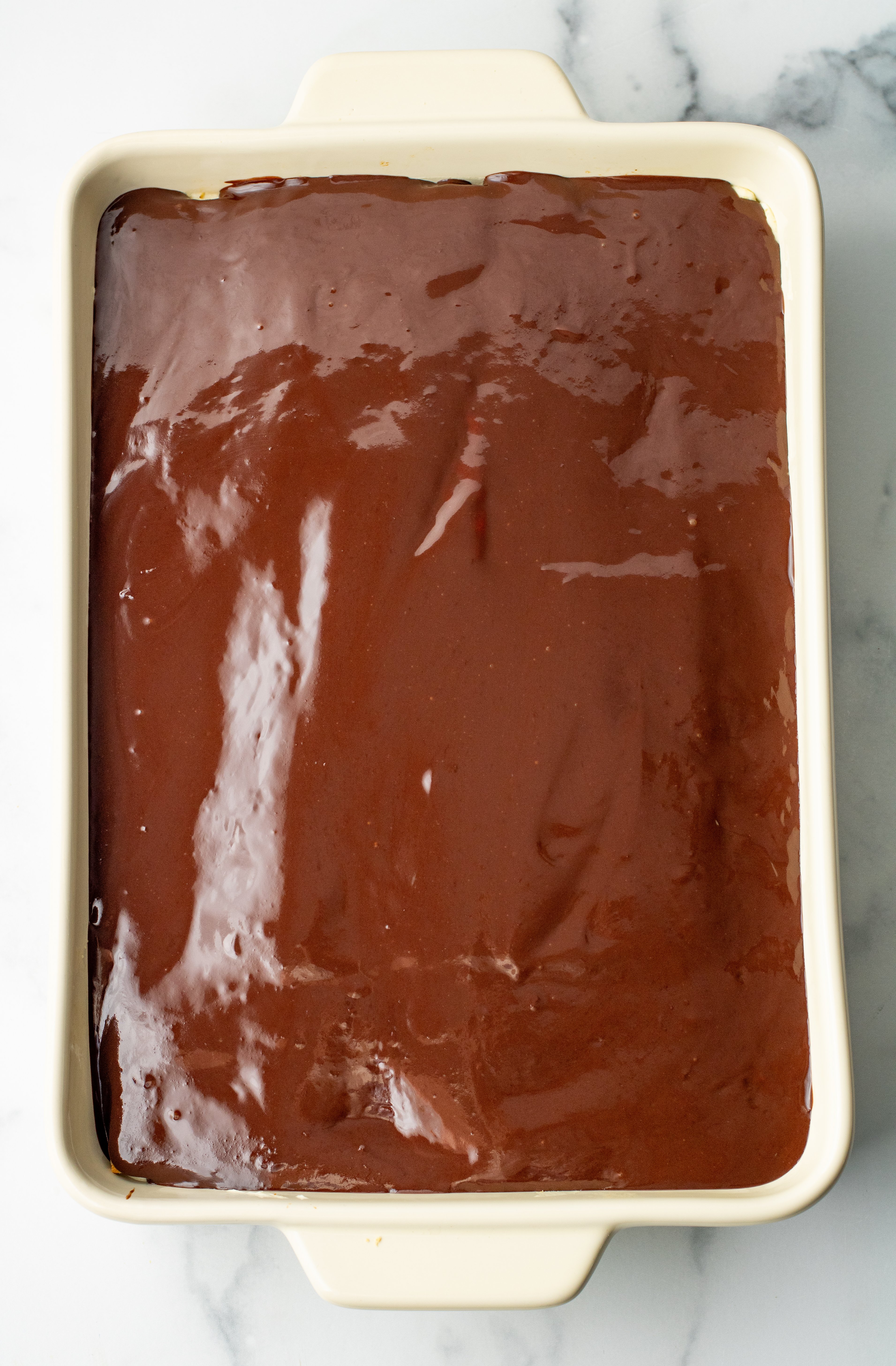 finished chocolate eclair cake covered in ganache in baking dish
