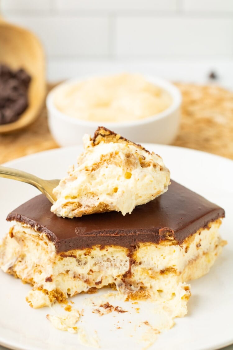 slice of chocolate eclair cake with a bite missing on a fork lying on top