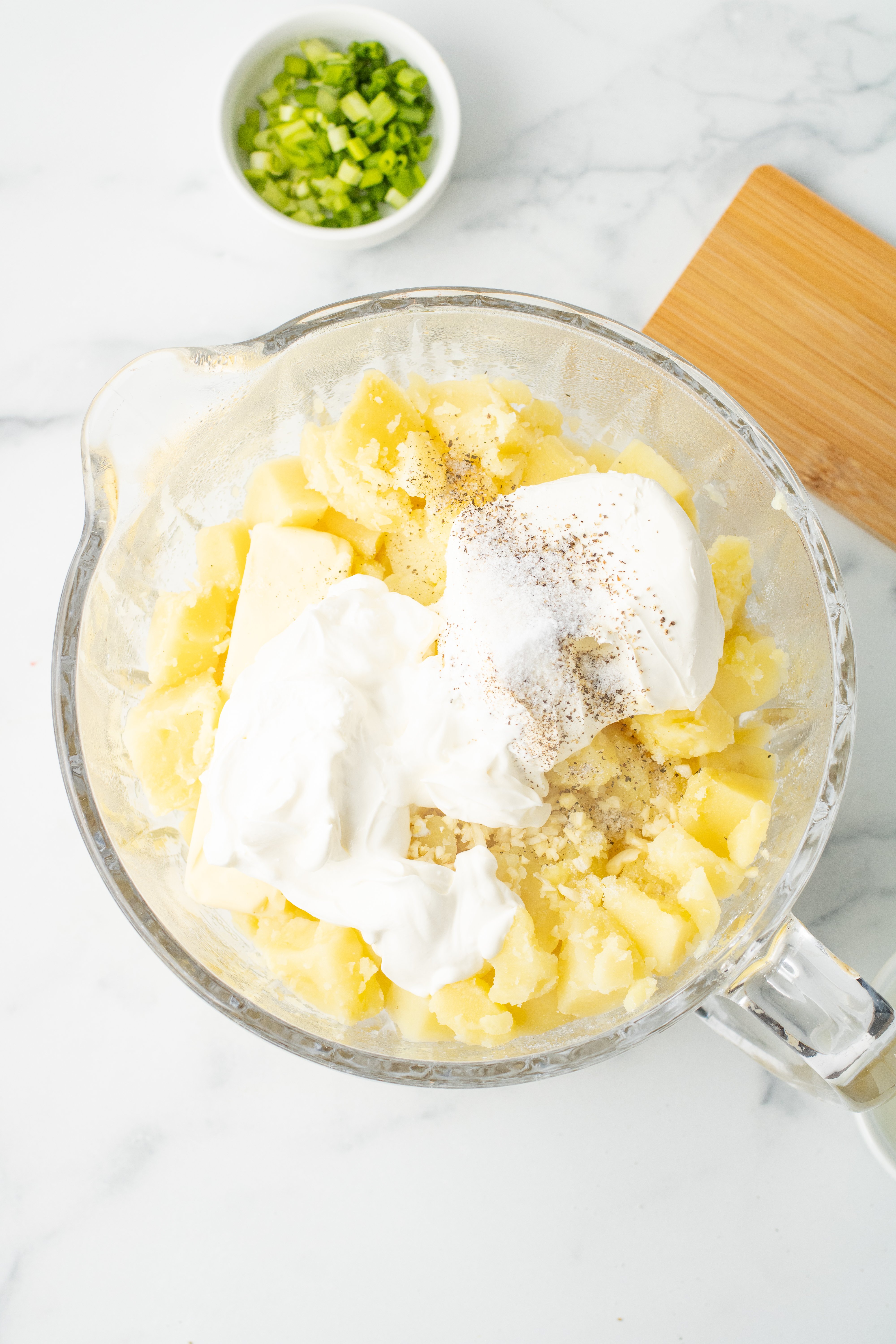 cream cheese, sour cream, butter, milk and garlic added to the potatoes in a large bowl