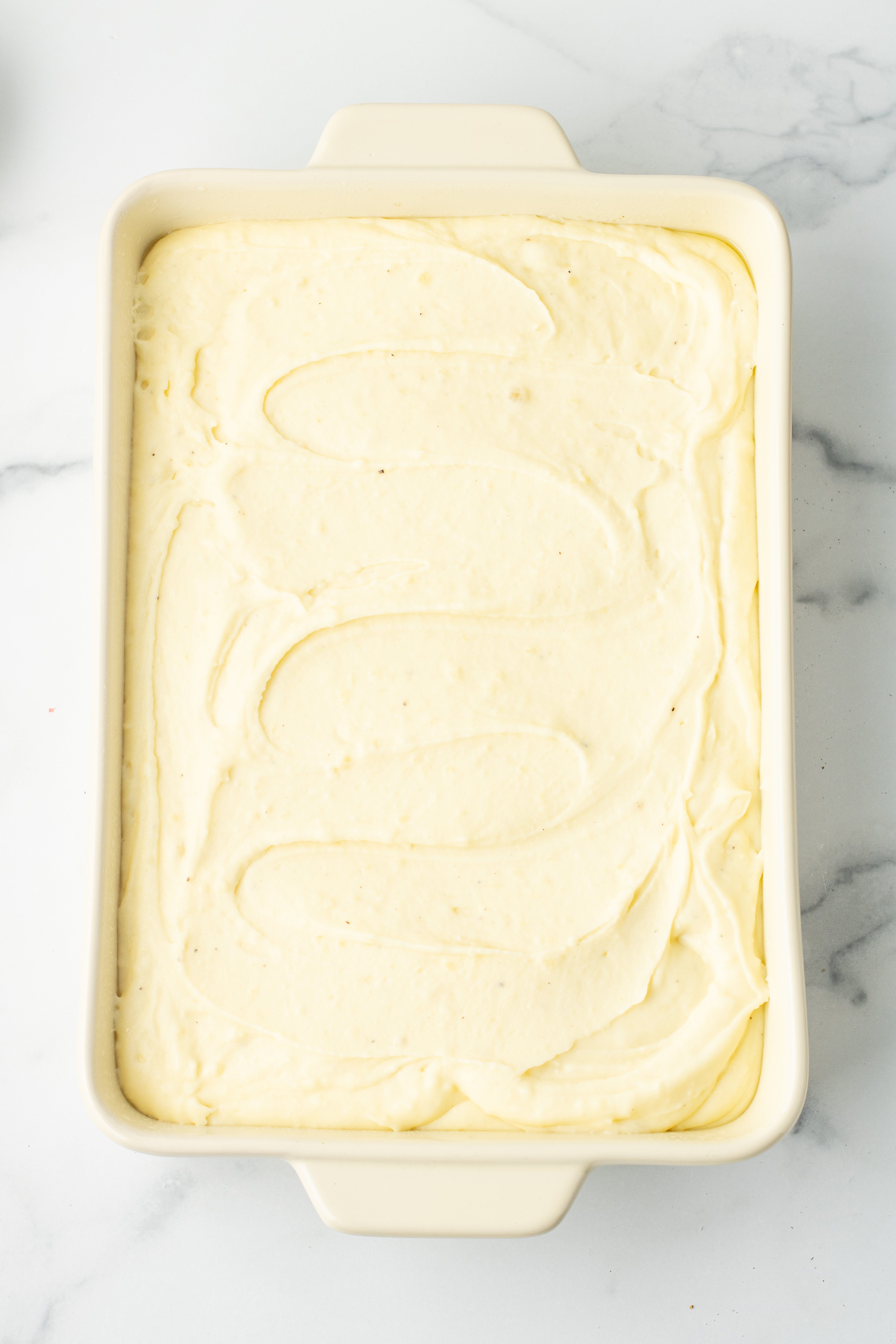 mashed potatoes with cream cheese spread in a baking dish