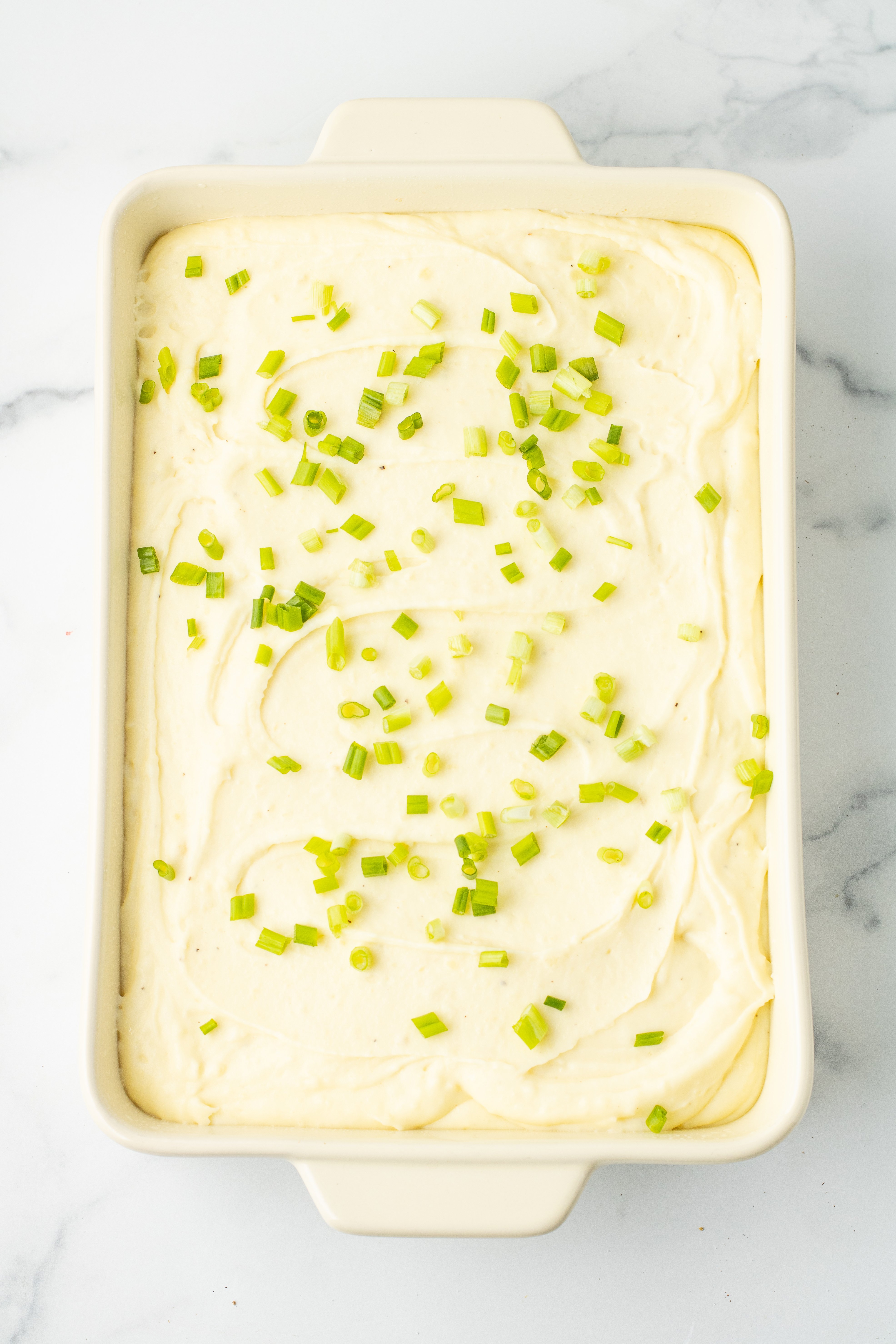 chives added on top of mashed potatoes in a baking dish
