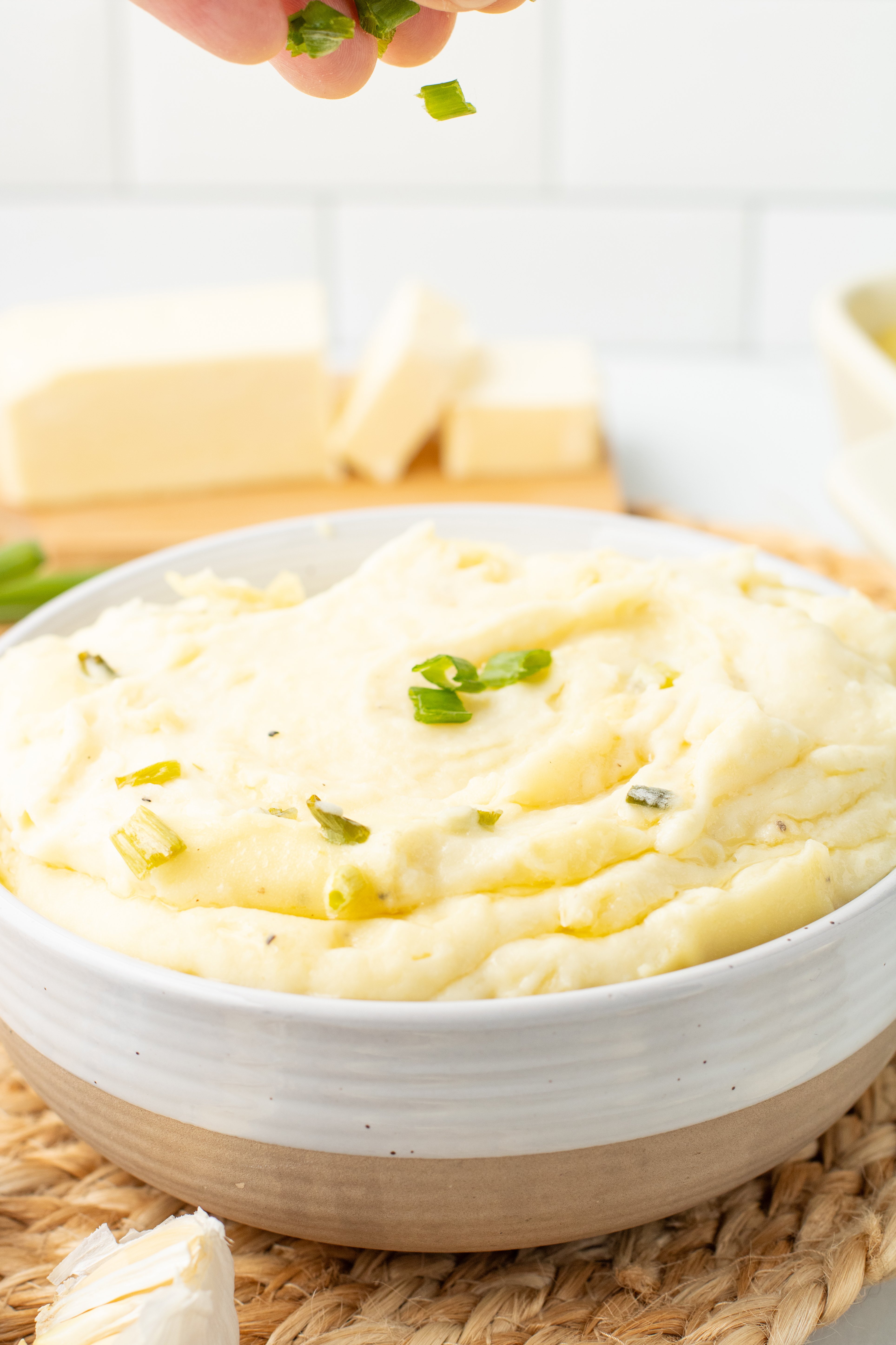 chives being sprinkled over mashed potatoes with cream cheese