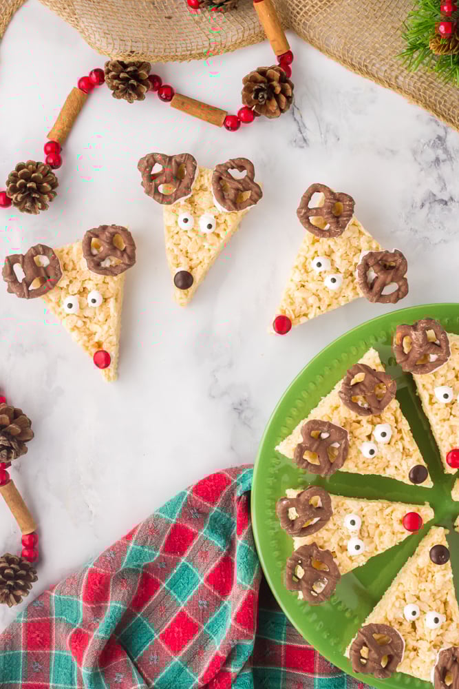 reindeer rice krispie treats on a plate and some on a white surface with christmas decor