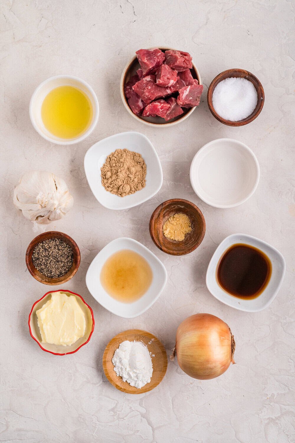 ingredients for slow cooker steak bites in individual bowls on a white surface