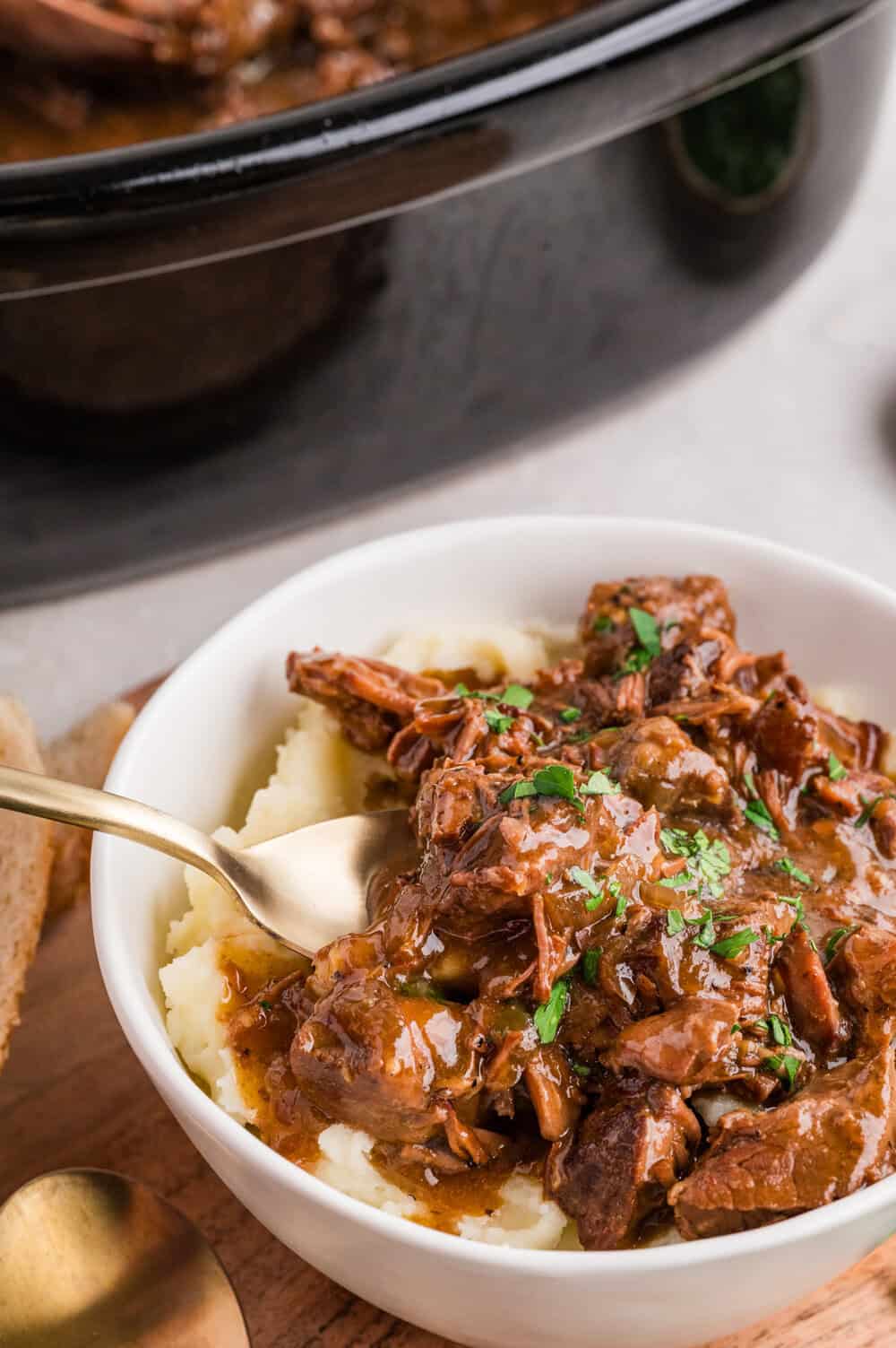 slow cooker steak bites in a bowl next to a slow cooker dish